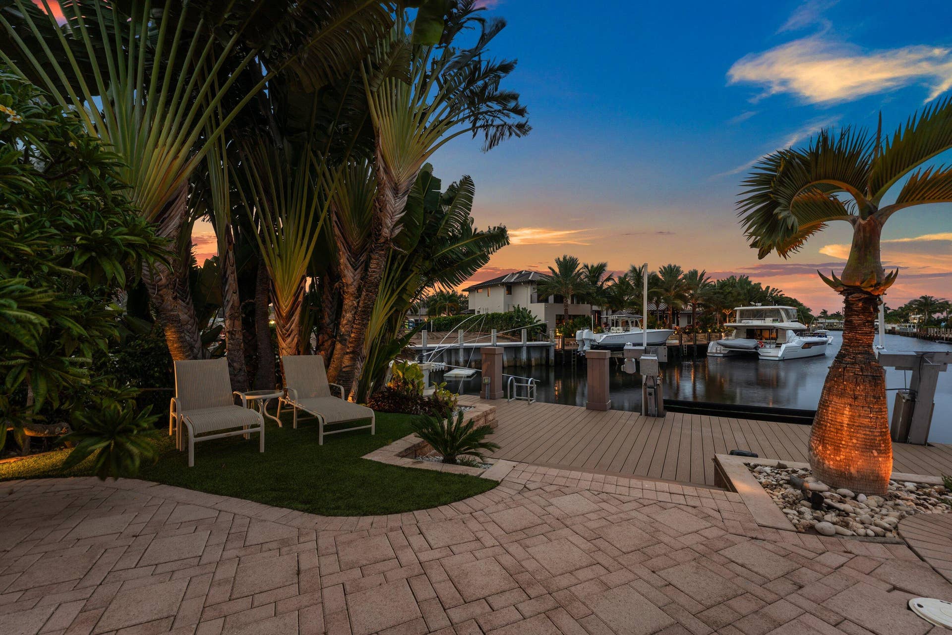 2761 NE 48TH Court, Lighthouse Point, FL 33064 Waterside patio featuring paver stones, a wooden dock, and mature tropical landscaping