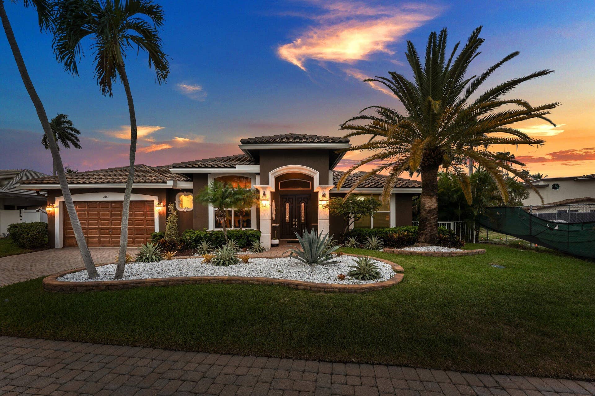 2761 NE 48TH Court, Lighthouse Point, FL 33064 Mediterranean-style residence featuring a tile roof, decorative white stone landscaping, and mature palm trees