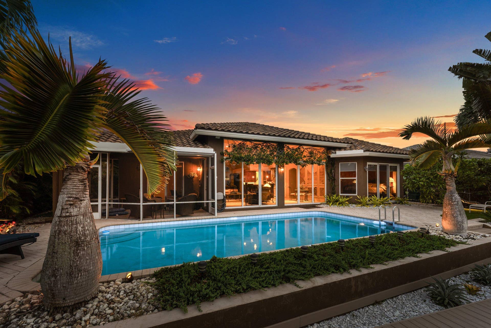 2761 NE 48TH Court, Lighthouse Point, FL 33064 Backyard oasis featuring a swimming pool with integrated steps, surrounded by paver decking and mature palm trees