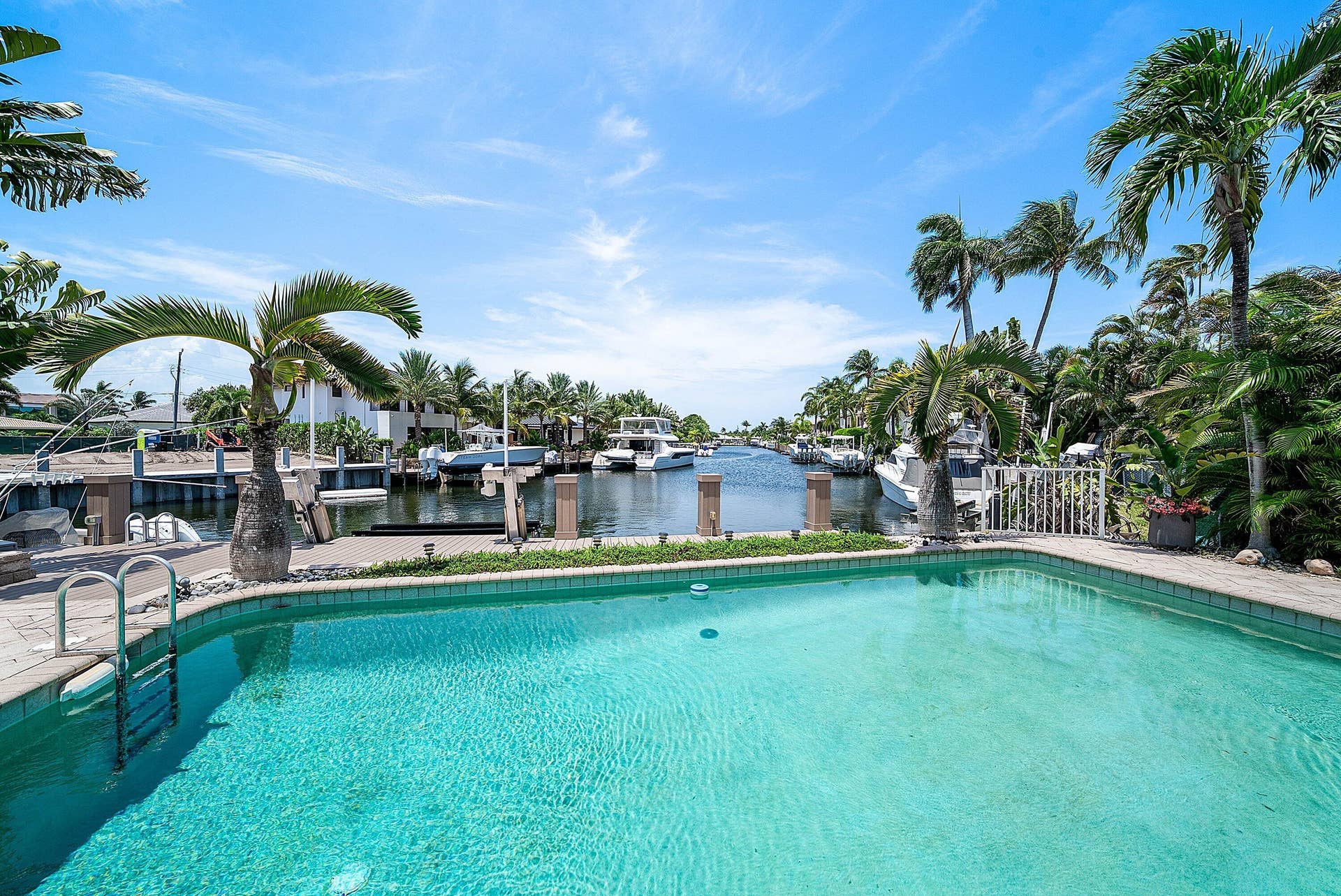 2761 NE 48TH Court, Lighthouse Point, FL 33064 Outdoor swimming pool with integrated steps, surrounded by a paved patio and lush tropical landscaping