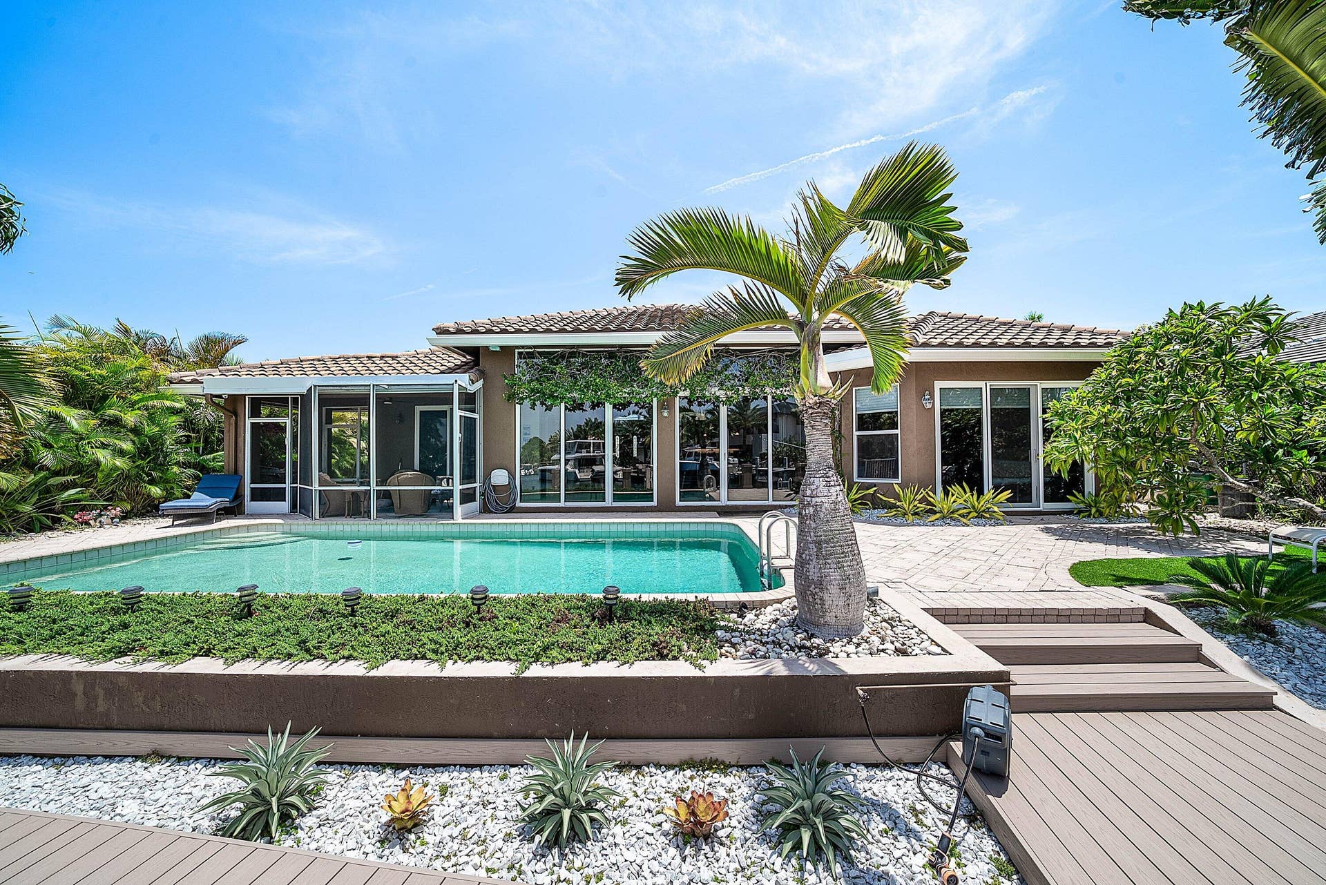 2761 NE 48TH Court, Lighthouse Point, FL 33064 Expansive backyard featuring a rectangular pool, screened patio, and multiple sliding glass doors