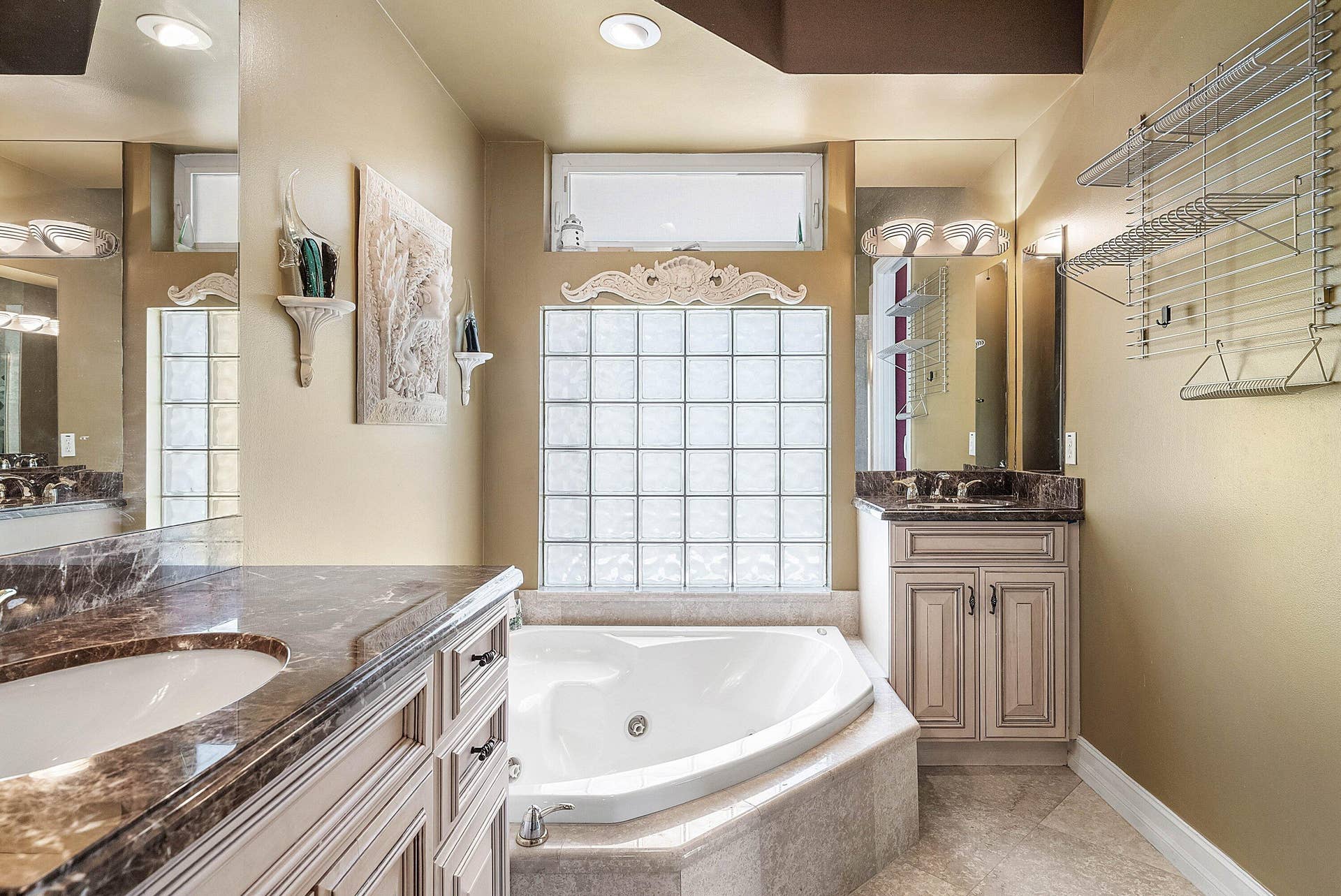 2761 NE 48TH Court, Lighthouse Point, FL 33064 Bathroom featuring a built-in corner soaking tub, glass block window, and dual vanity areas with stone countertops
