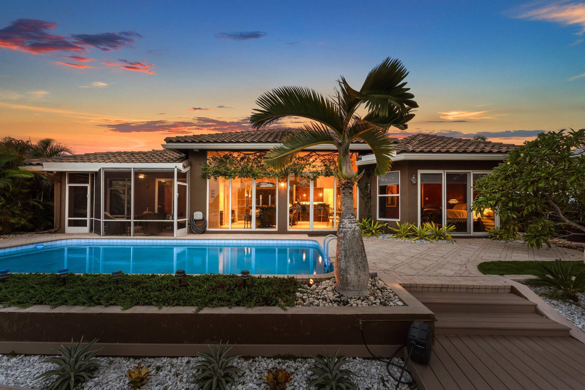 2761 NE 48TH Court, Lighthouse Point, FL 33064 Rear exterior showcasing a rectangular swimming pool, screened-in patio, and a tiled roofline