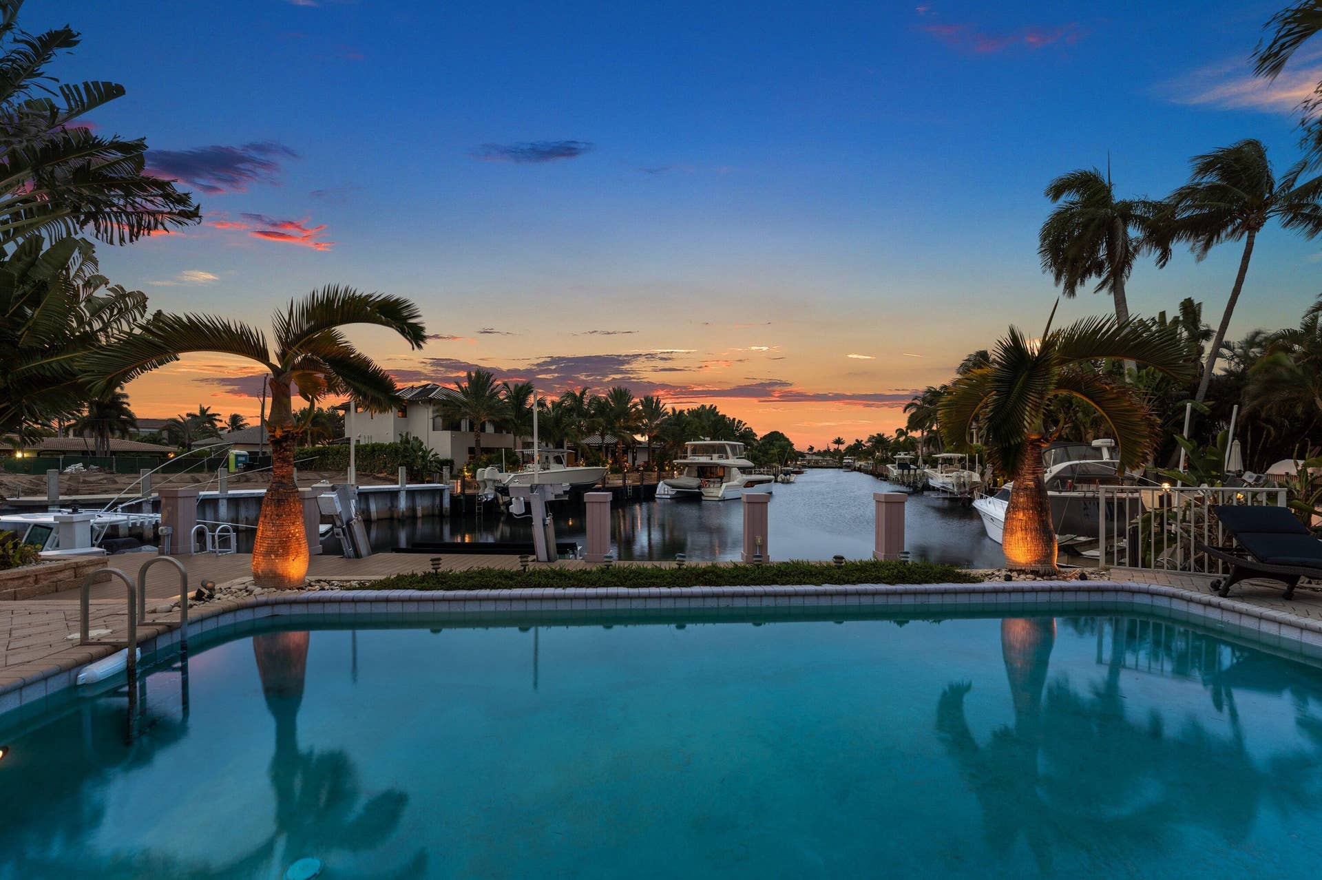 2761 NE 48TH Court, Lighthouse Point, FL 33064 Waterfront property featuring a private swimming pool with integrated steps, a brick paver pool deck, and mature palm trees