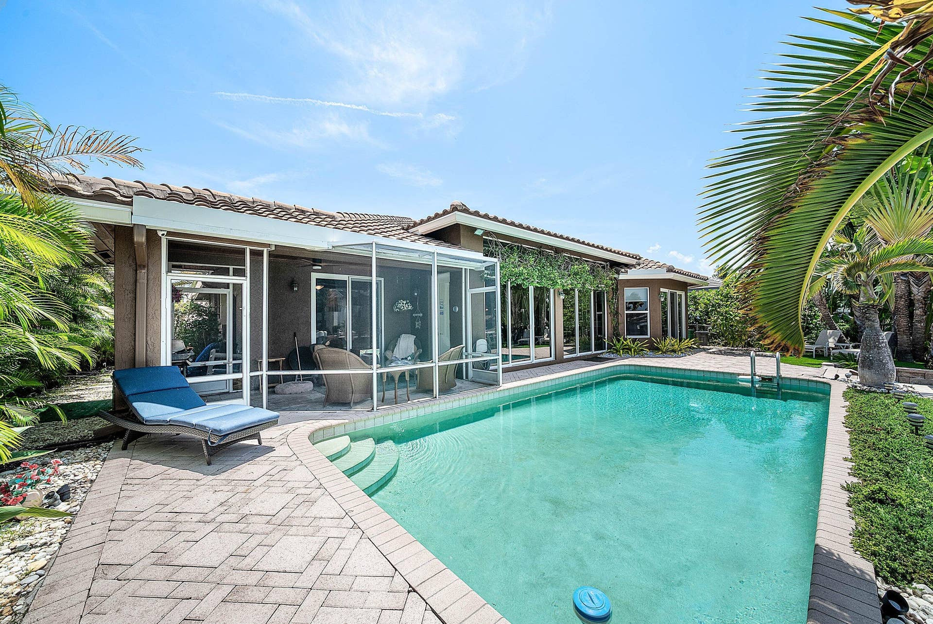 2761 NE 48TH Court, Lighthouse Point, FL 33064 Outdoor swimming pool with integrated steps, surrounded by a paved patio and lush landscaping