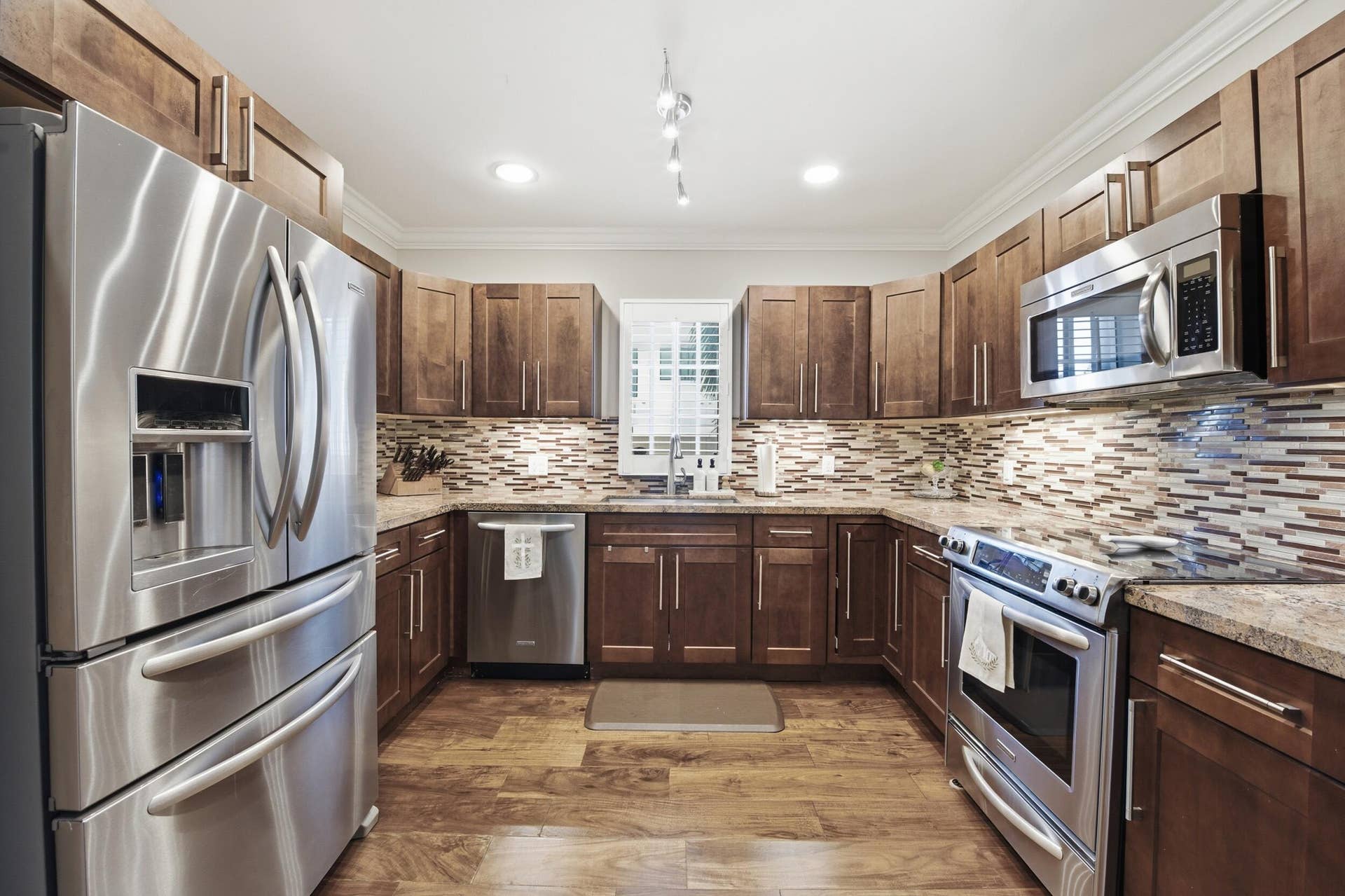 917 NE 3RD Street, #9, Fort Lauderdale, Fort Lauderdale, FL 33301 U-shaped kitchen featuring dark wood cabinetry, stainless steel appliances, a mosaic tile backsplash, and granite countertops