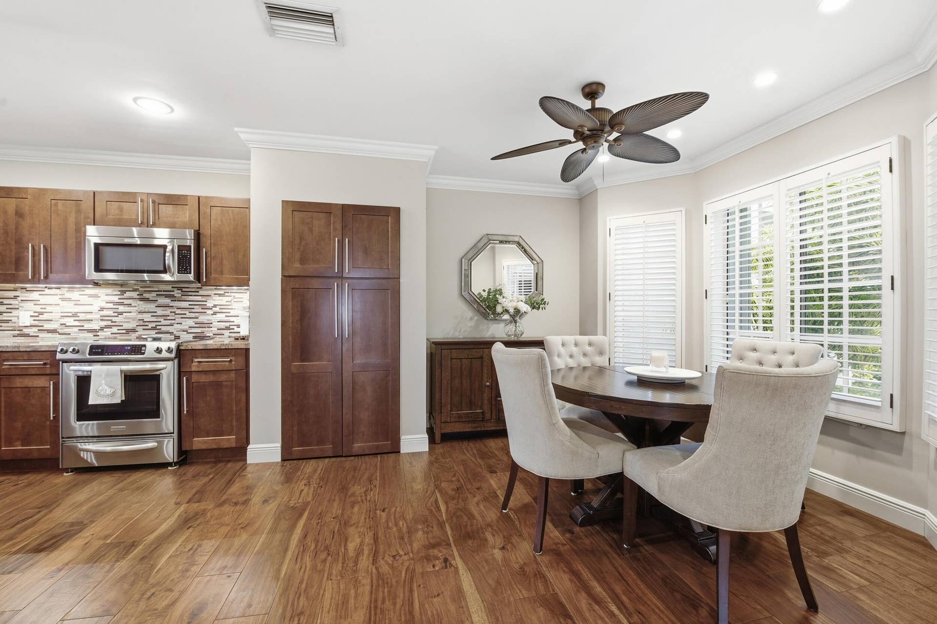 917 NE 3RD Street, #9, Fort Lauderdale, Fort Lauderdale, FL 33301 Kitchen and dining area featuring wood-finish flooring, stainless steel appliances, a mosaic tile backsplash, and extensive cabinetry