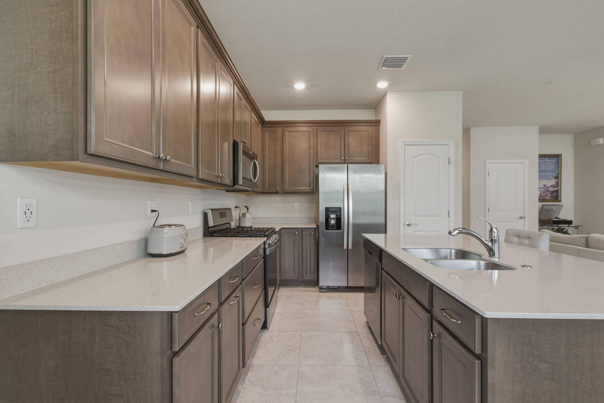 4601 Pinehurst Trail E, Oakland Park, FL 33309 Kitchen featuring light wood-finish cabinetry with brushed nickel hardware, light-toned countertops, and stainless steel appliances