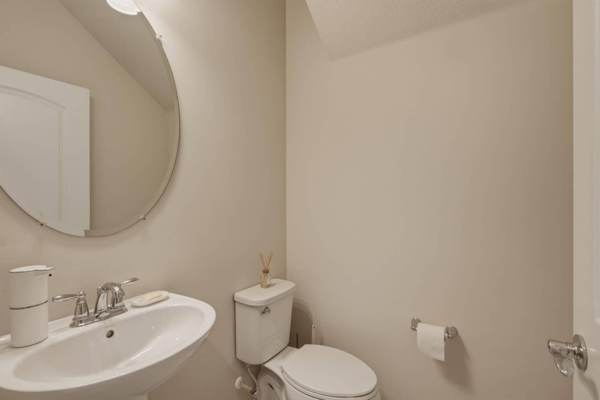 4601 Pinehurst Trail E, Oakland Park, FL 33309 Pedestal sink with chrome faucet, complemented by a large circular mirror and overhead lighting
