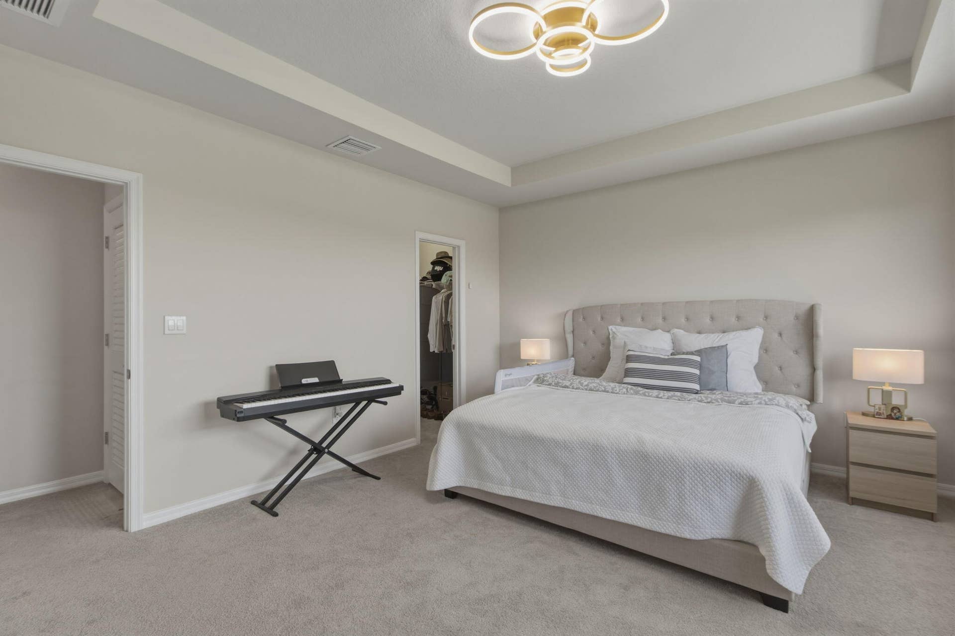 4601 Pinehurst Trail E, Oakland Park, FL 33309 Neutral-toned bedroom featuring a tray ceiling with a contemporary flush-mount fixture, light gray carpeting, and a built-in closet with bi-fold doors