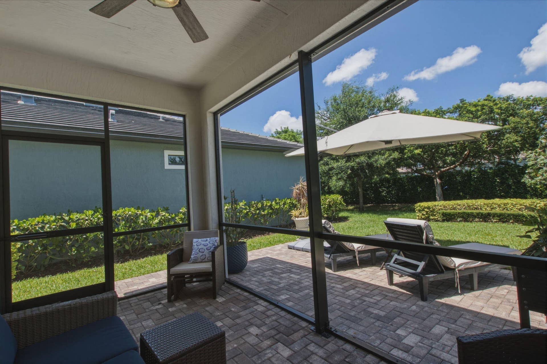 4601 Pinehurst Trail E, Oakland Park, FL 33309 Screened patio featuring a ceiling fan, paver flooring, and a landscaped yard
