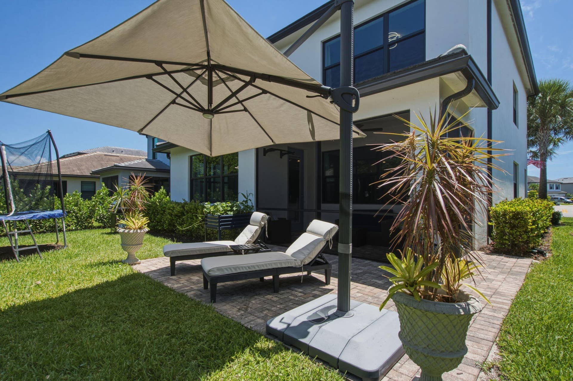 4601 Pinehurst Trail E, Oakland Park, FL 33309 Expansive exterior patio featuring paver flooring, a large offset umbrella, and direct access to a manicured lawn