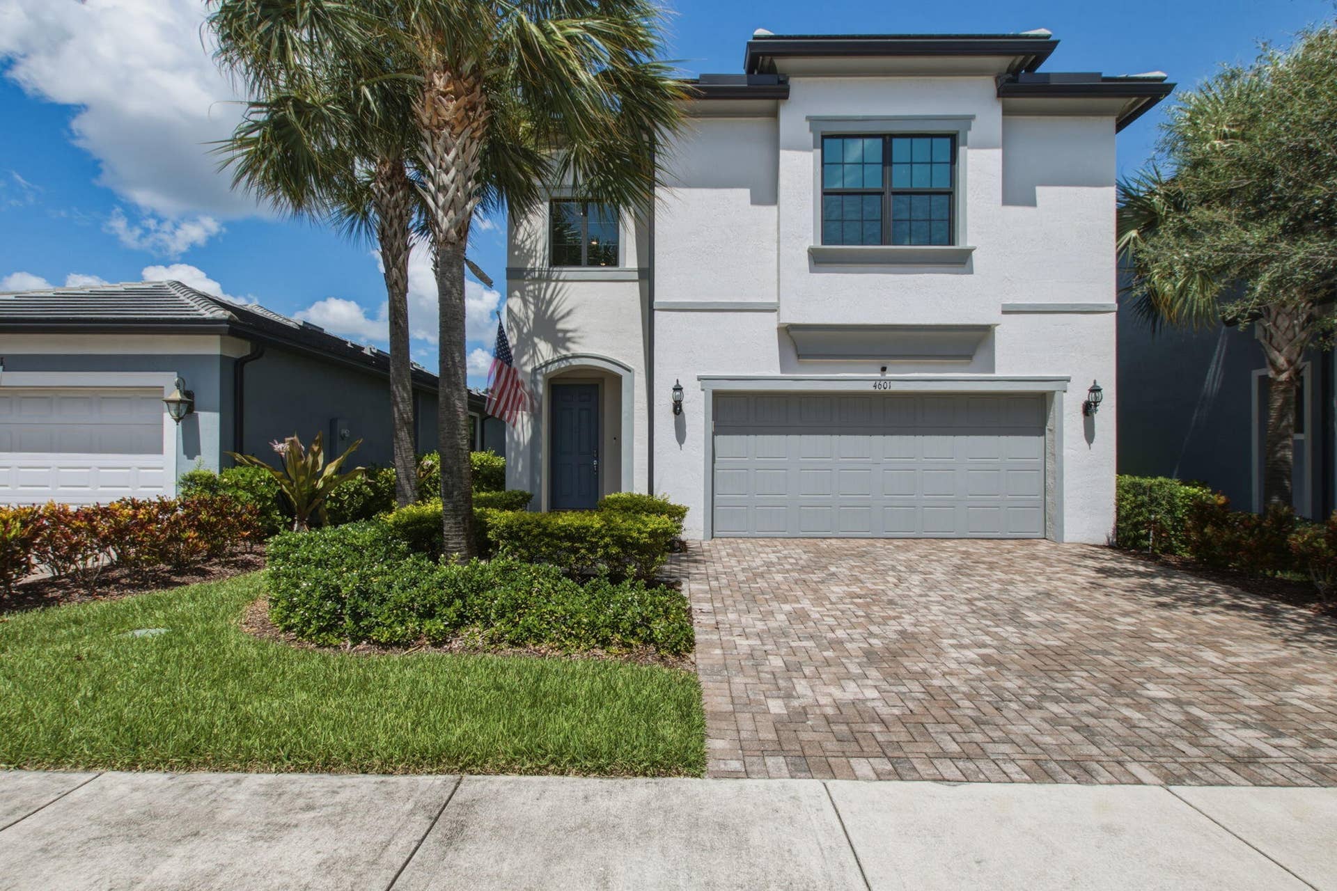 4601 Pinehurst Trail E, Oakland Park, FL 33309 Contemporary stucco facade with a two-car garage, paver driveway, arched entry, and dark-framed windows