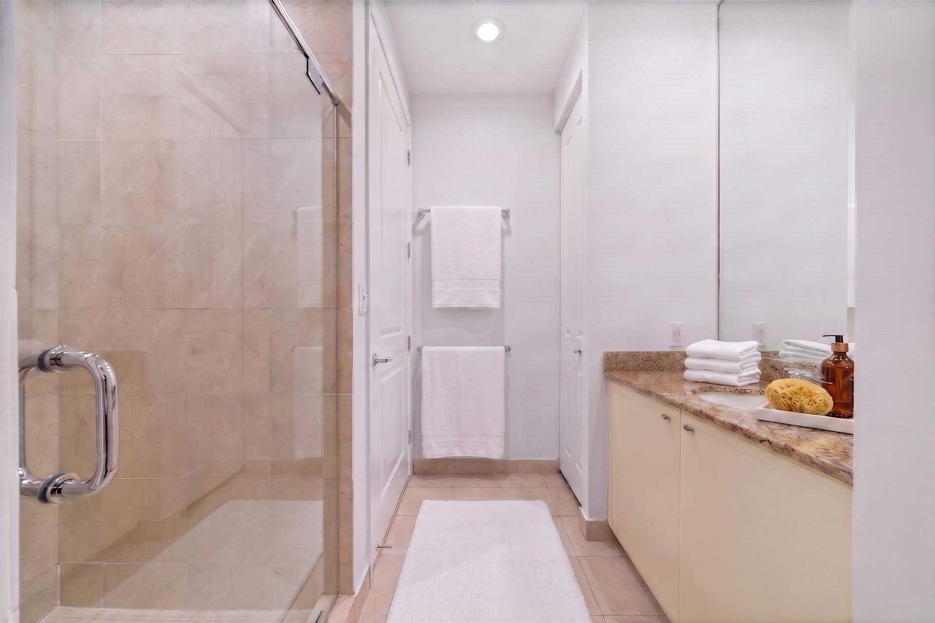 610 W Las Olas Boulevard, #115N, Fort Lauderdale, FL 33312 Alternate bathroom view showcasing the granite vanity, mirrored wall, glass-enclosed shower & built-in linen storage.