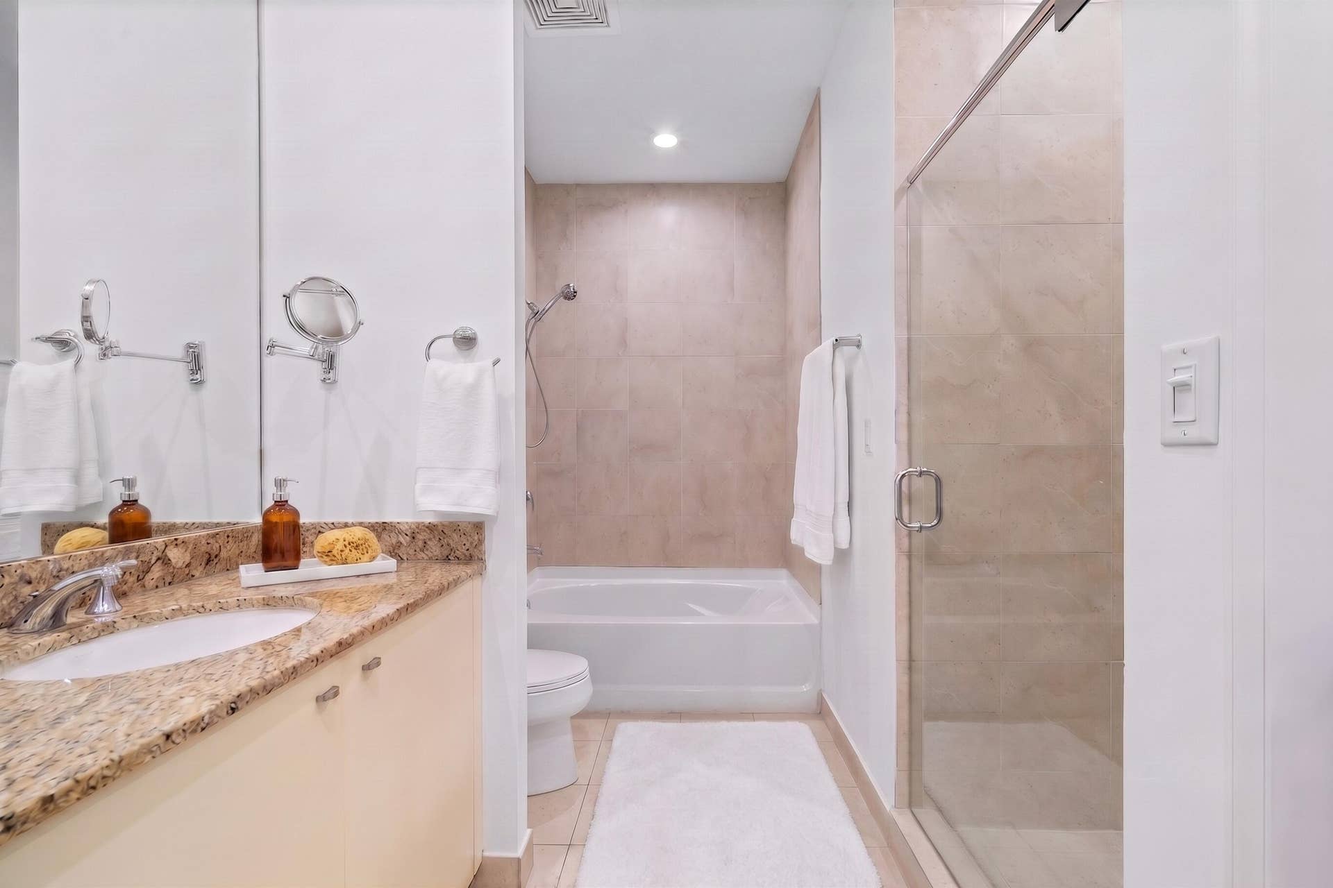 610 W Las Olas Boulevard, #115N, Fort Lauderdale, FL 33312 Spacious bathroom with a granite-topped vanity, large soaking tub & separate glass-enclosed walk-in shower with neutral tile finishes.