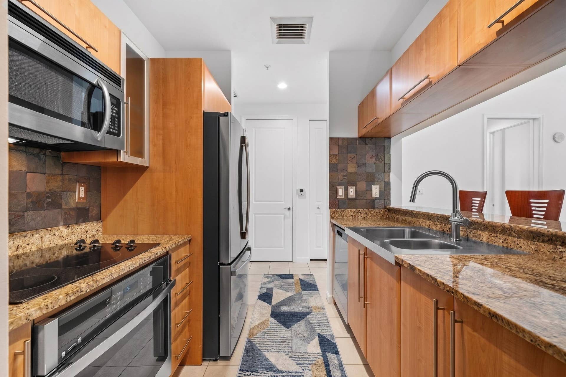 610 W Las Olas Boulevard, #115N, Fort Lauderdale, FL 33312 Alternate kitchen view featuring a glass electric cooktop, built-in oven & microwave, double-basin sink, pantry & breakfast-bar pass-through.