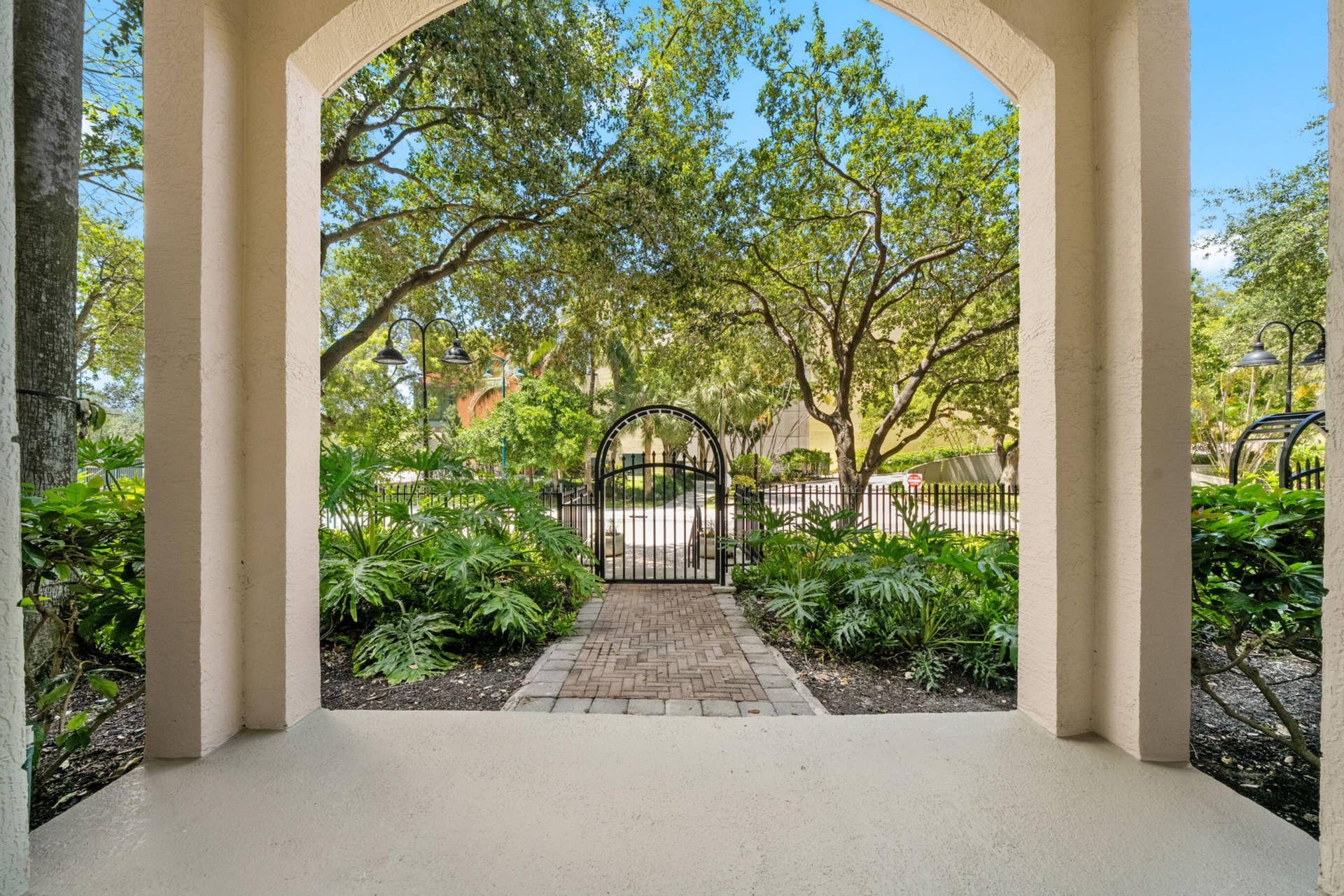 610 W Las Olas Boulevard, #115N, Fort Lauderdale, FL 33312 Covered private patio framed by lush landscaping, with a brick-paver path leading to the gated entrance on West Las Olas Boulevard.