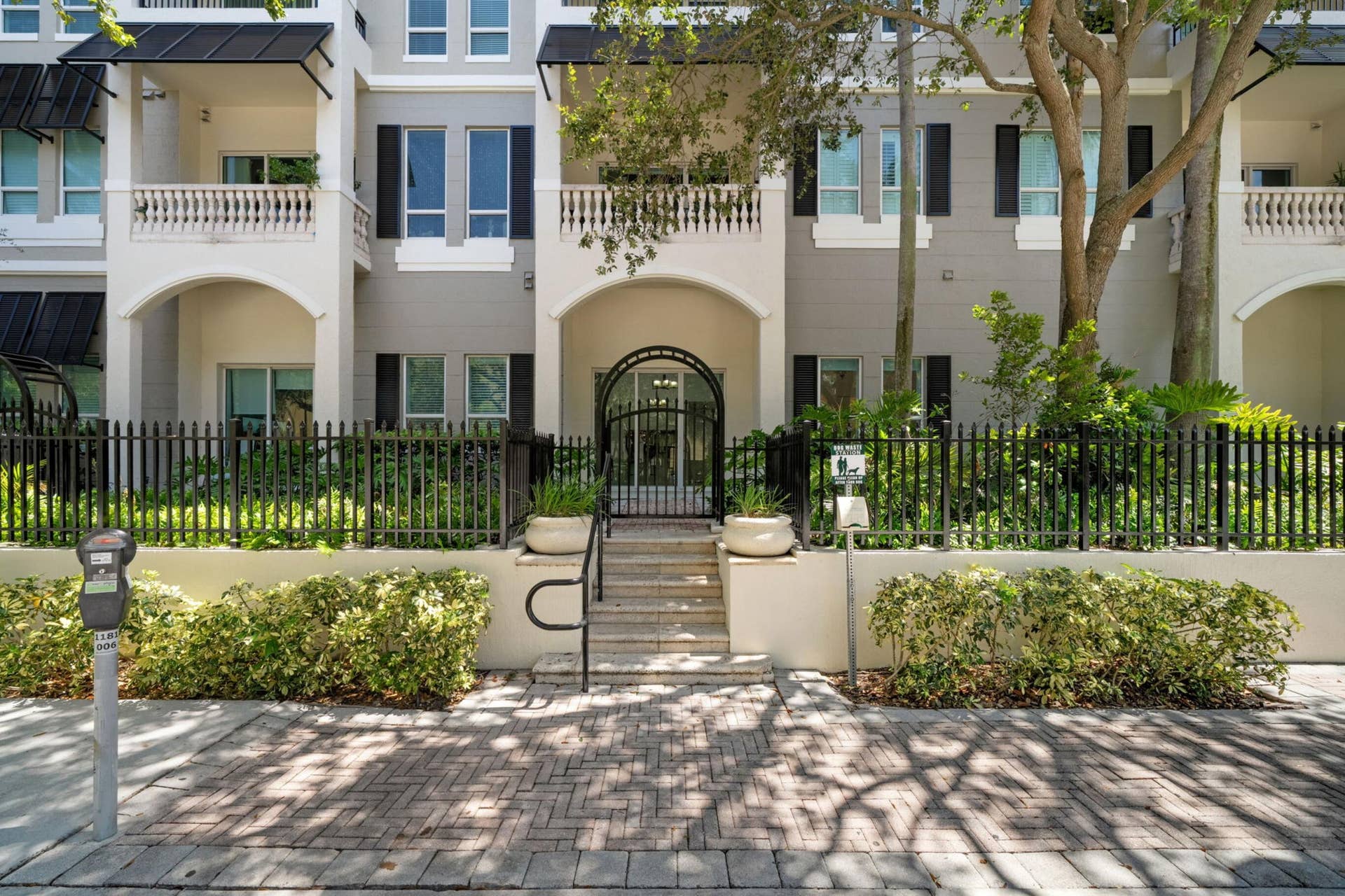 610 W Las Olas Boulevard, #115N, Fort Lauderdale, FL 33312 Street-level view of Residence 115Ns private gated entrance, shaded by mature trees along West Las Olas Boulevard.
