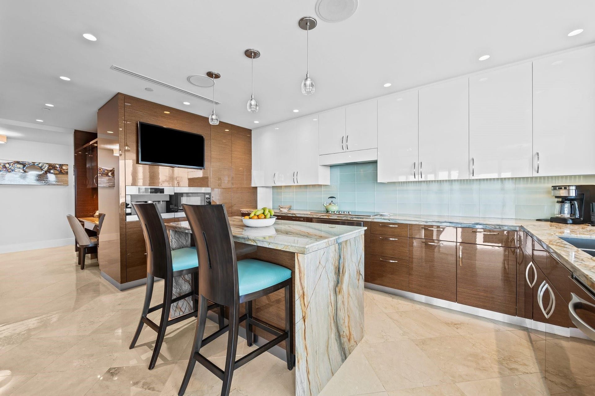 3055 Harbor Drive, #1403, Fort Lauderdale, FL 33316 Gourmet kitchen featuring a waterfall island with stone countertop, contrasting high-gloss white and wood-finish cabinetry, a tiled backsplash, and recessed lighting