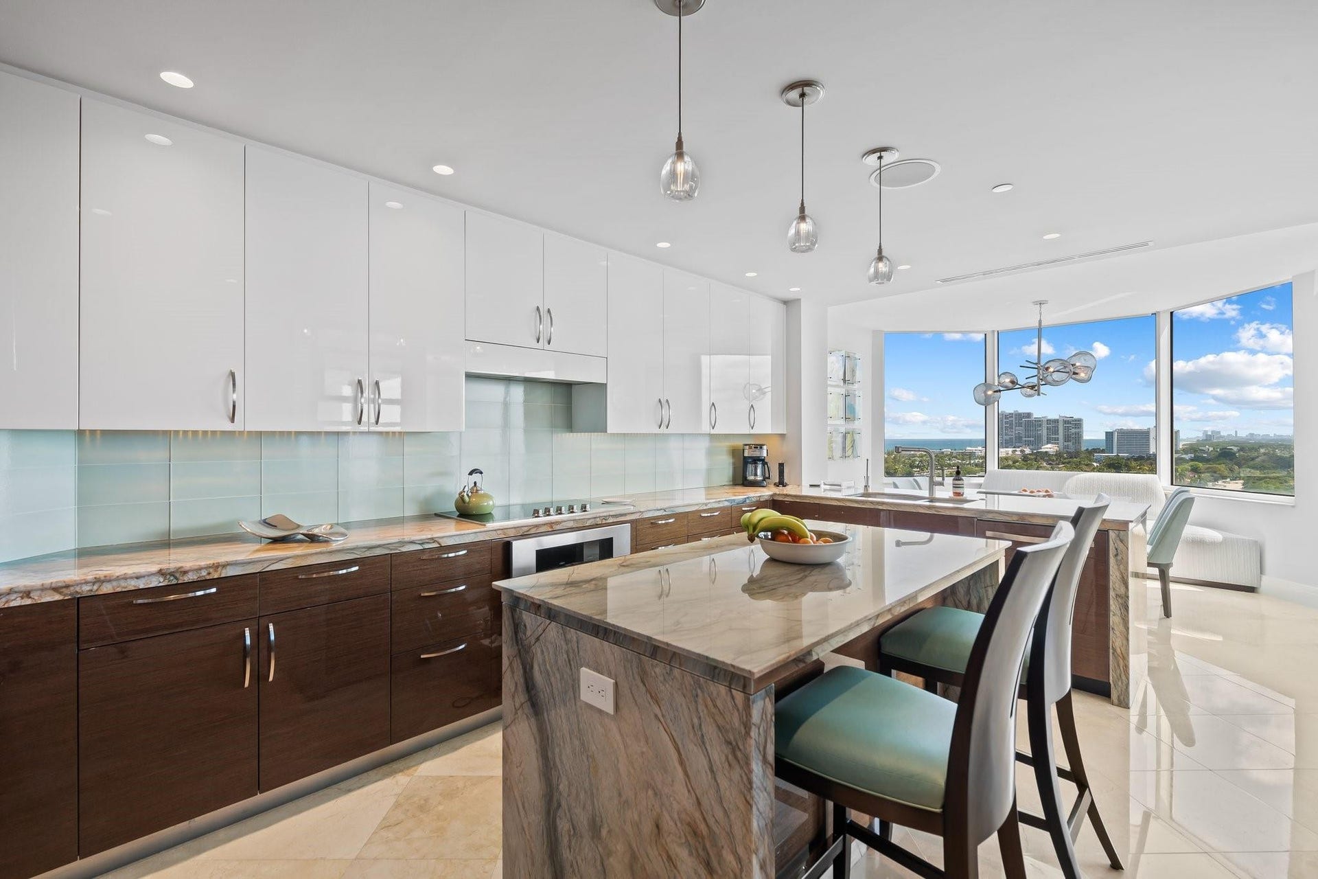 3055 Harbor Drive, #1403, Fort Lauderdale, FL 33316 Spacious kitchen featuring an expansive island with a stone countertop, two-tone cabinetry with upper white gloss and lower wood-finish, a light blue tile backsplash, and recessed lighting