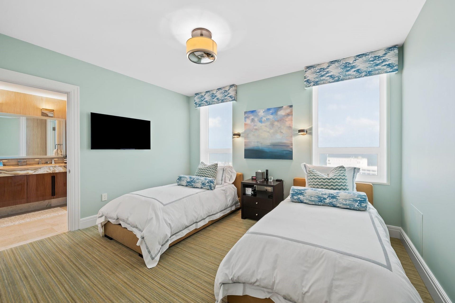 3055 Harbor Drive, #1403, Fort Lauderdale, FL 33316 Room featuring two windows with patterned valances, a mounted television, a ceiling light fixture, and horizontal wood-finish flooring