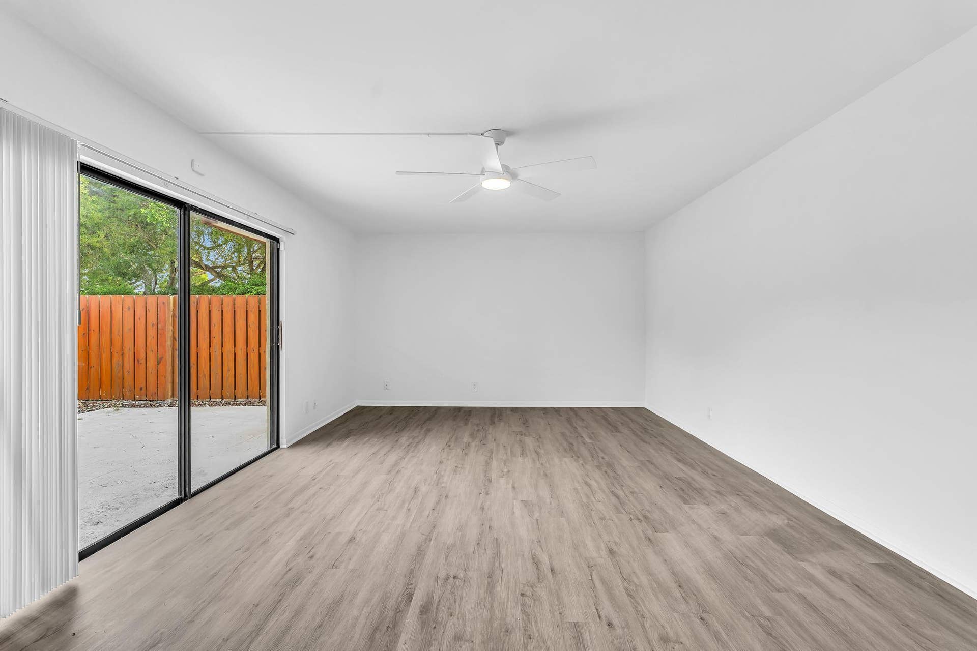 Expansive room featuring wood-finish flooring and a ceiling fan