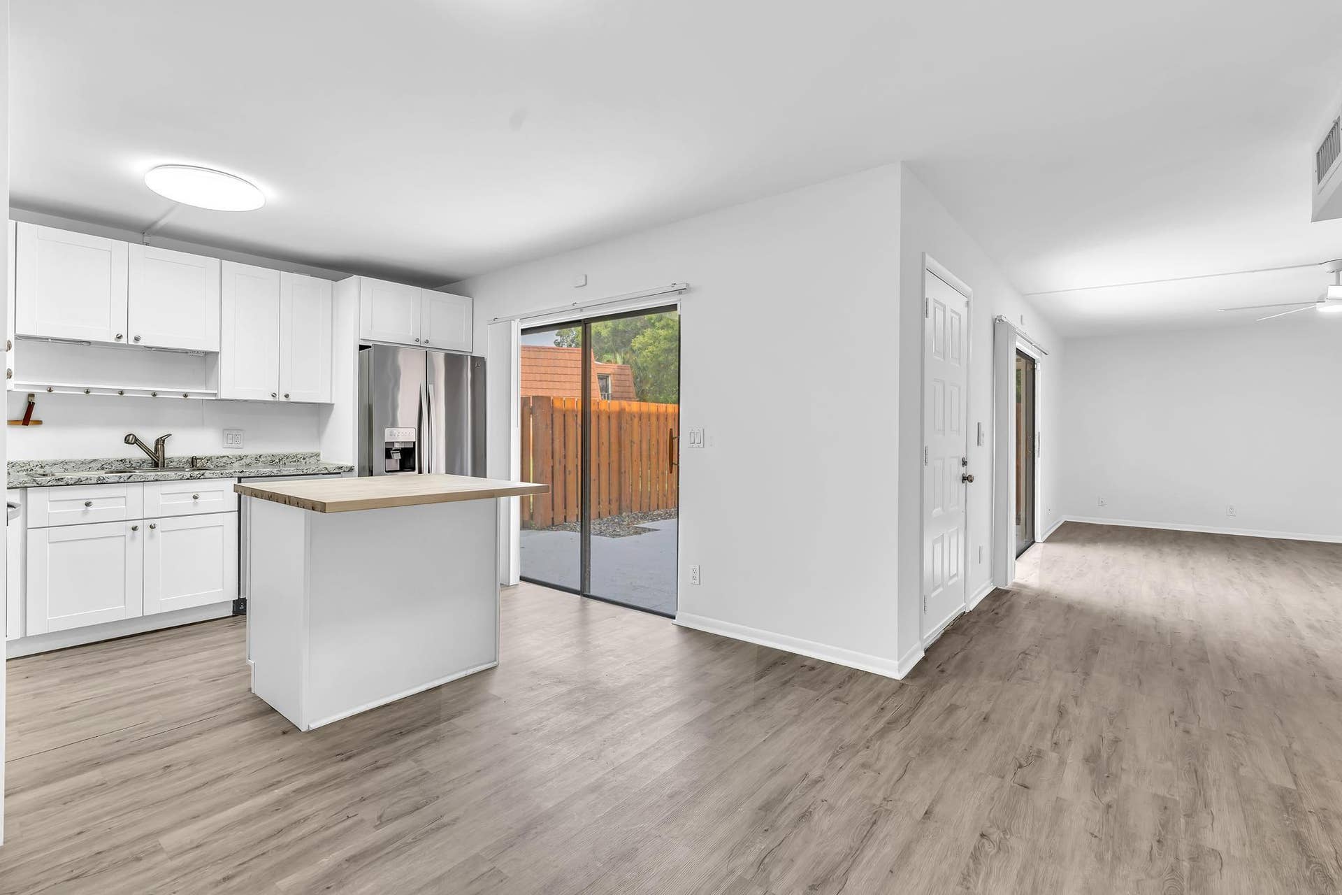 Modern kitchen with white cabinetry and granite countertops, featuring an island with a wood-finish top