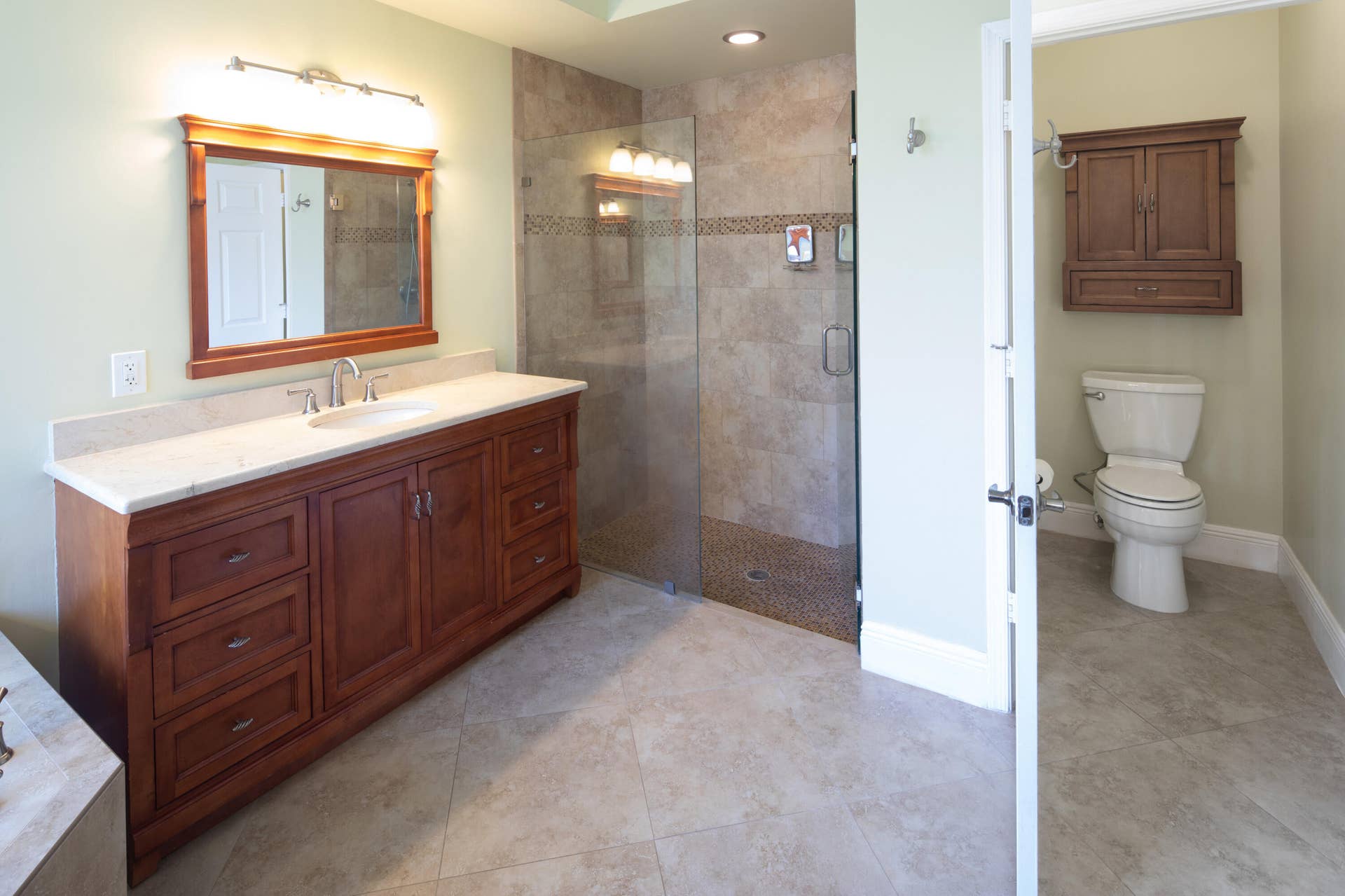 Alternate view of the primary bathroom highlighting the dual-sink vanity, walk-in shower, and private water closet.