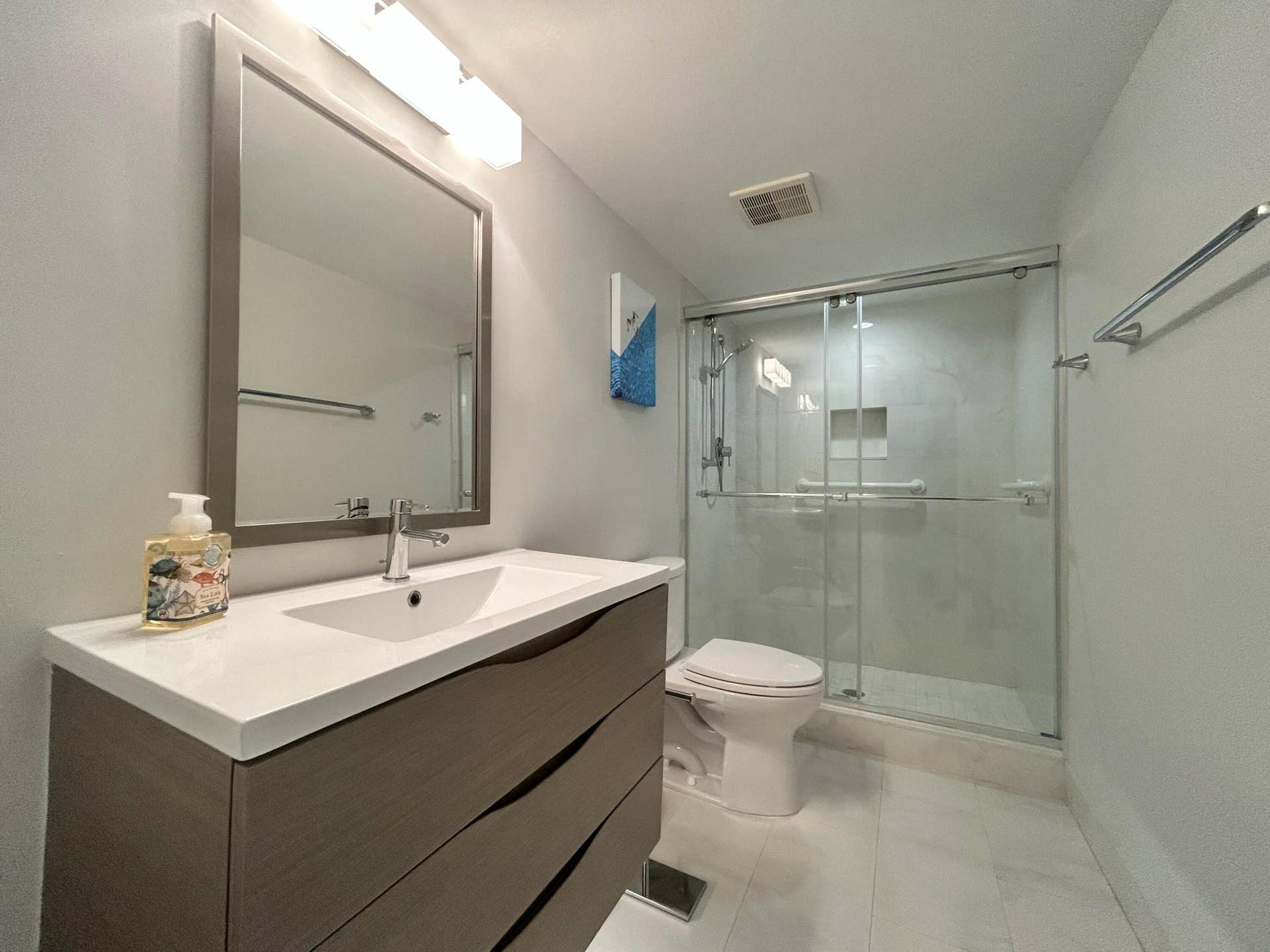 Bathroom featuring a contemporary vanity with an integrated sink, framed mirror, and chrome fixtures