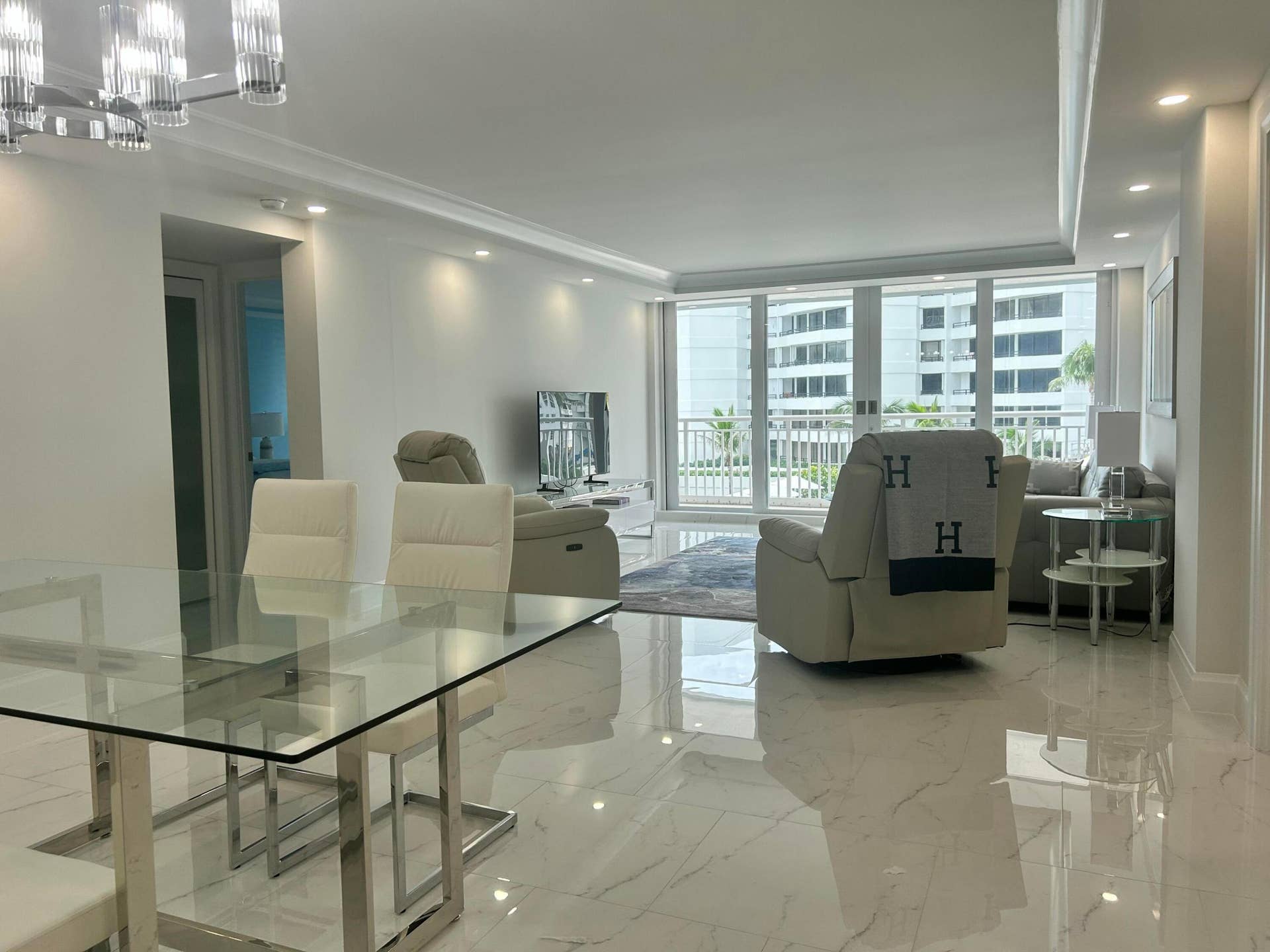 Open-concept living area with polished tile flooring and crown molding