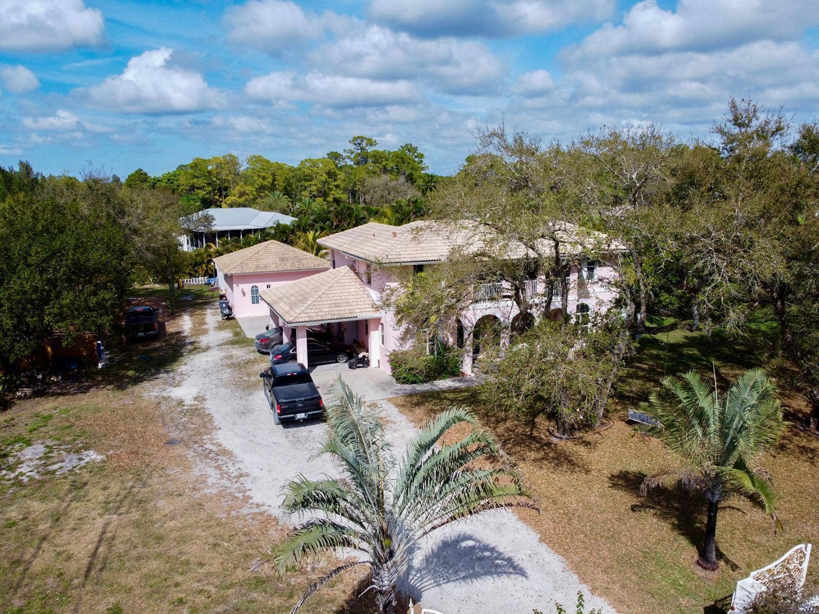 Pink-toned stucco exterior residence featuring multiple architectural arches and a barrel tile roof