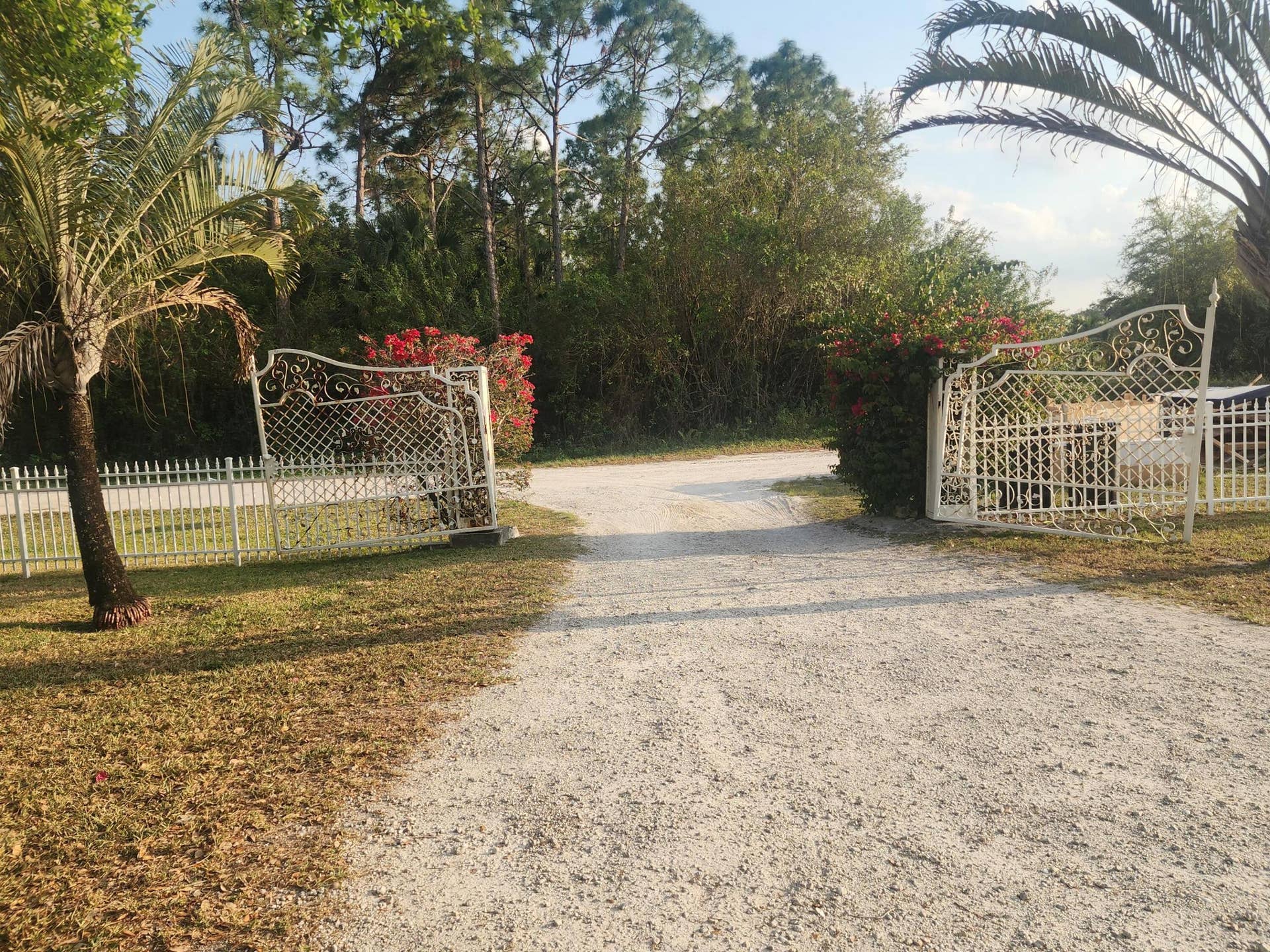 Wrought iron gates opening onto a gravel driveway