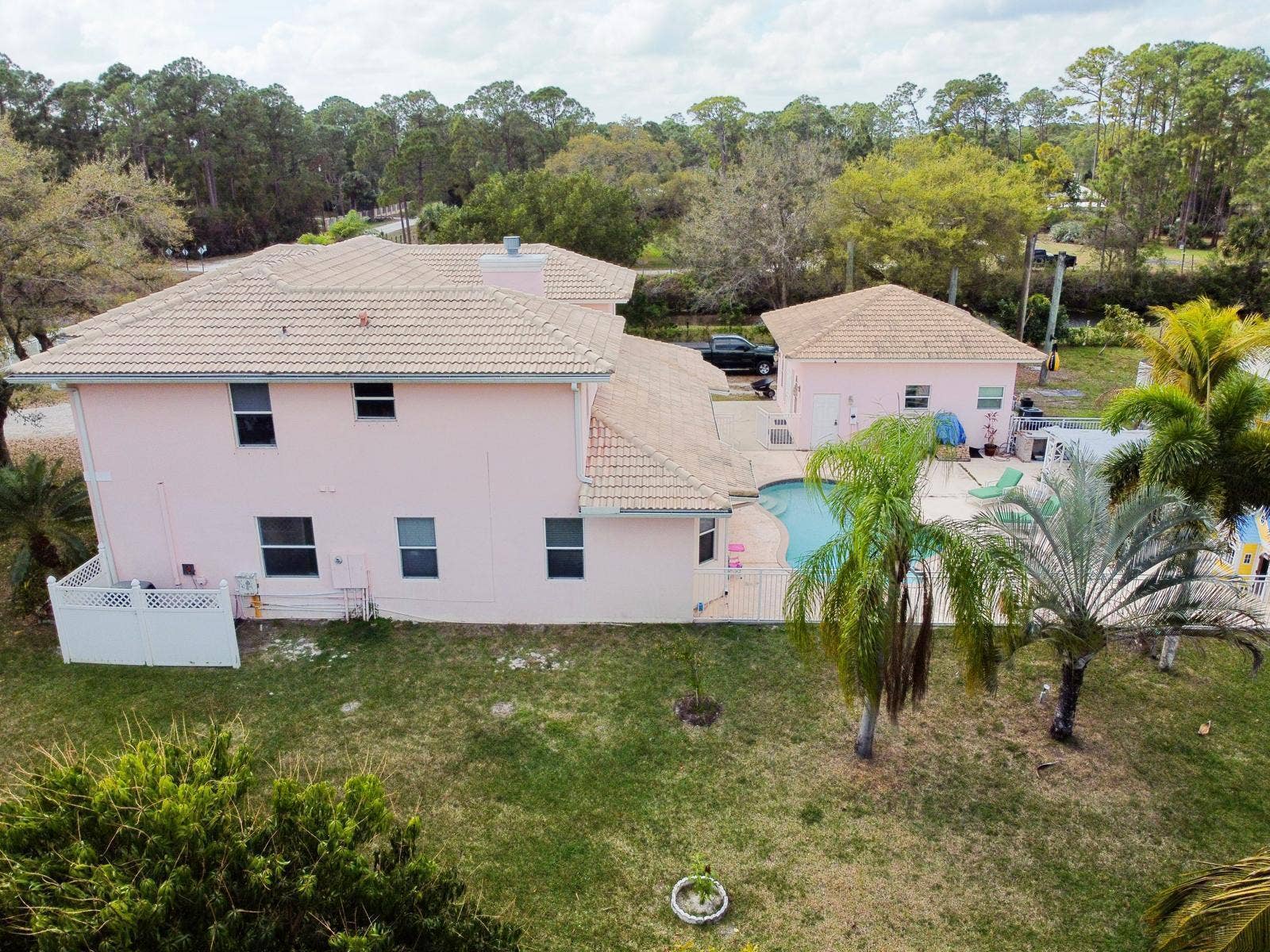 Exterior stucco residence featuring a tile roof, private swimming pool, and mature palm trees
