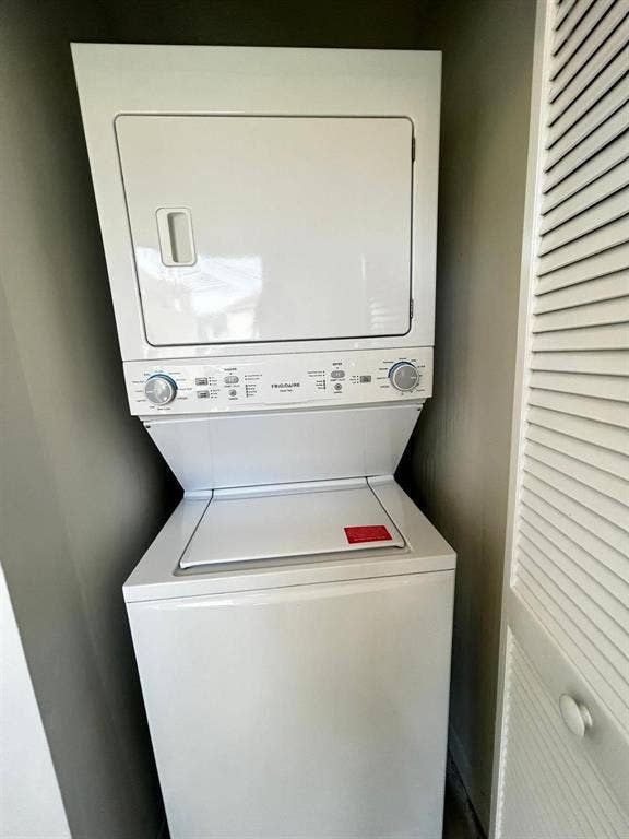 White stacked laundry unit featuring a top-load washer and front-load dryer