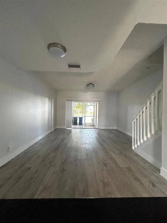 Spacious interior featuring wood-finish flooring, white walls, and a sliding glass door providing outdoor access