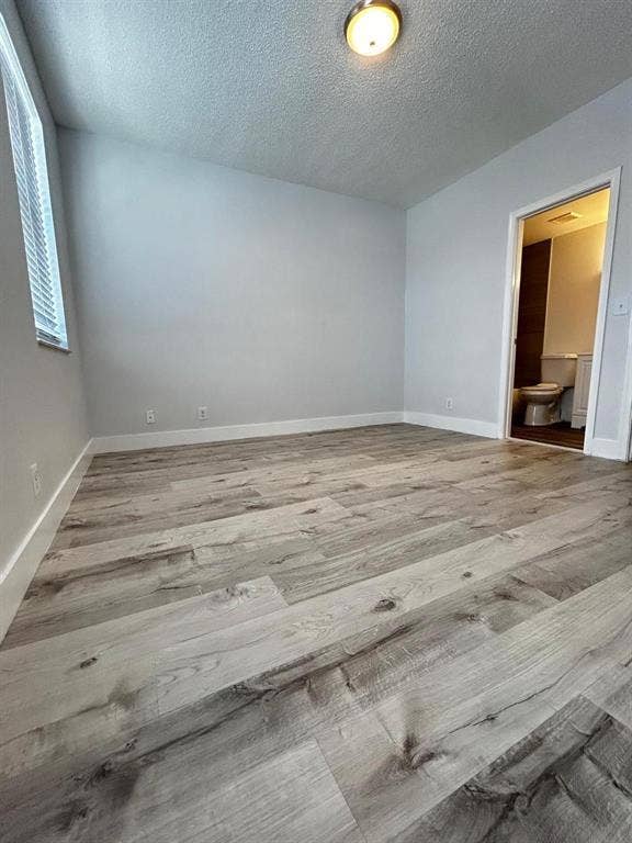 Spacious room featuring wide plank wood-finish flooring, white baseboards, and neutral wall tones