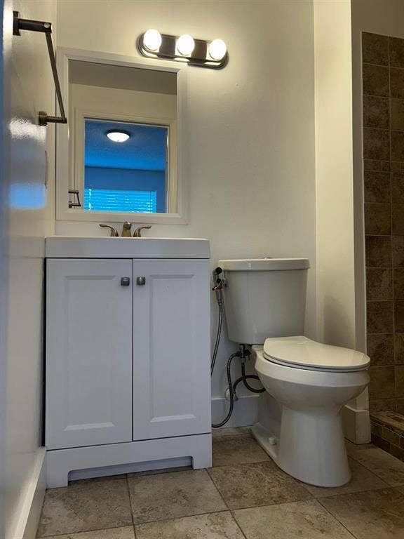 Bathroom featuring a white vanity with integrated sink, rectangular mirror, and a three-light vanity fixture