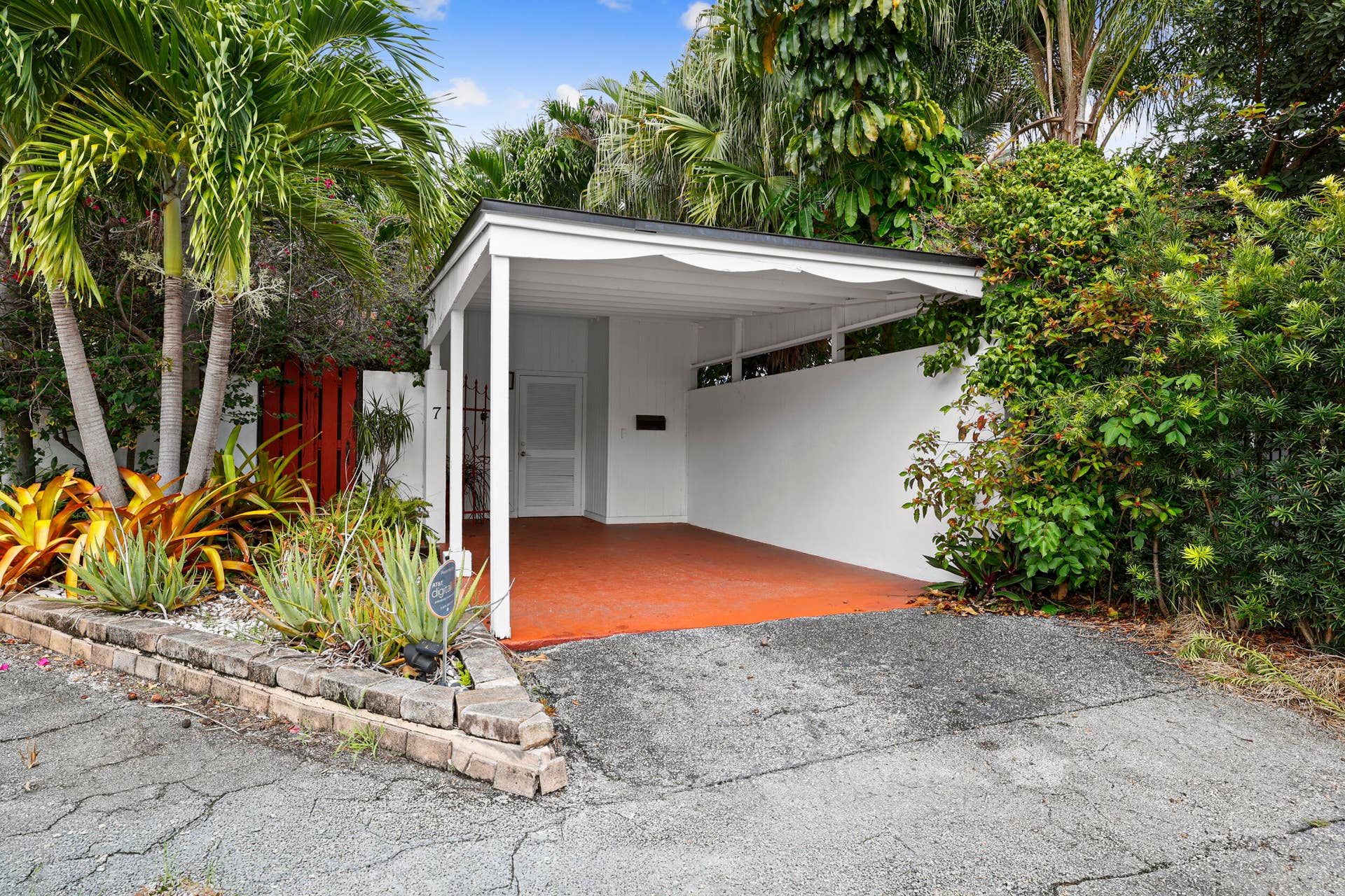 7 Middlesex Drive, Wilton Manors, FL 33305 Modern carport featuring a clean-lined white structure with an open design and orange polished concrete flooring