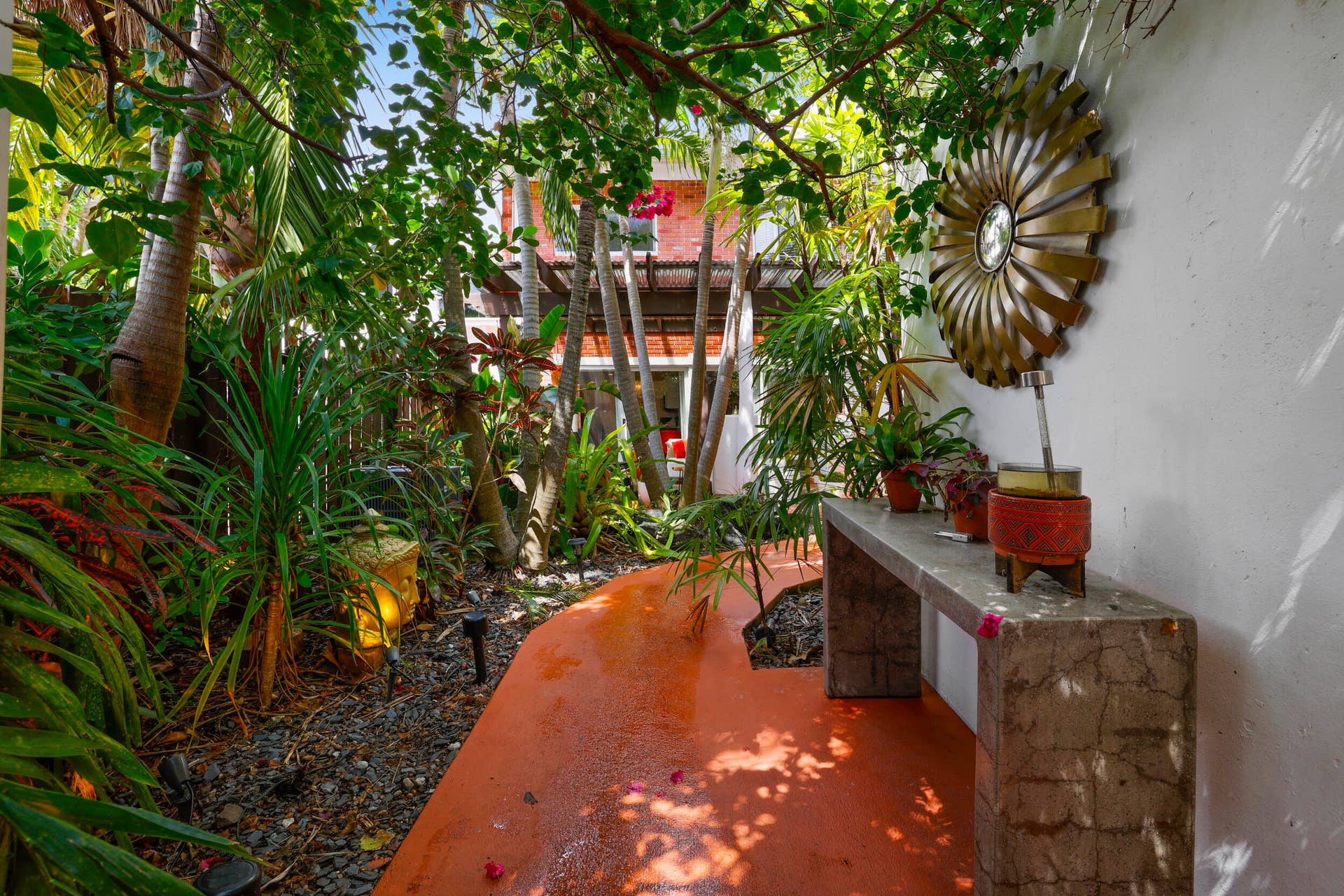 7 Middlesex Drive, Wilton Manors, FL 33305 Lush tropical courtyard oasis featuring mature palms and layered greenery, terracotta-toned concrete flooring, and white stucco walls