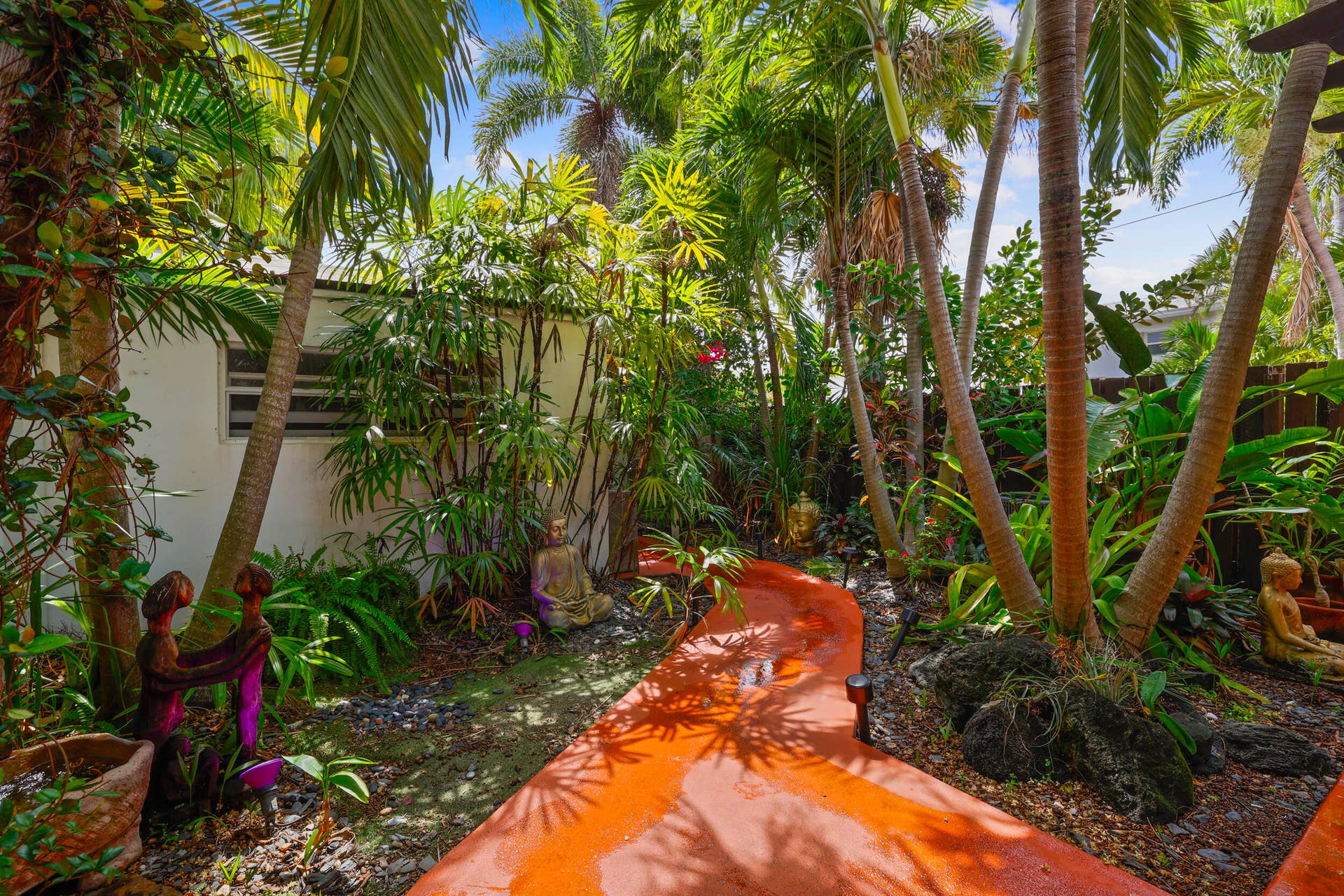7 Middlesex Drive, Wilton Manors, FL 33305 Lush tropical landscape featuring mature palm trees, vibrant plantings, and natural stone pathways throughout the grounds