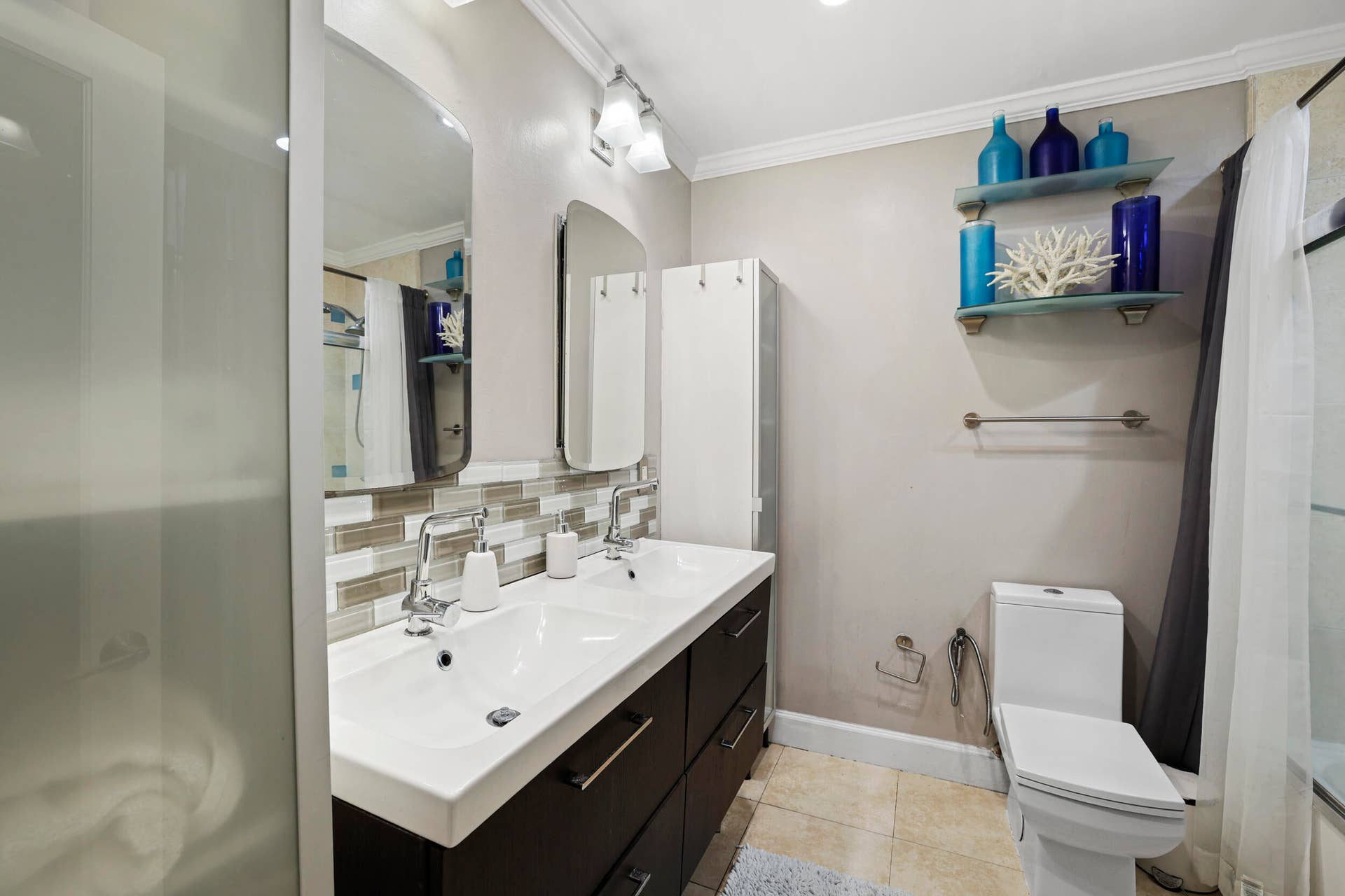 7 Middlesex Drive, Wilton Manors, FL 33305 Modern bathroom featuring a dual-sink vanity with white quartz countertop, matte black hardware, and dark cabinetry