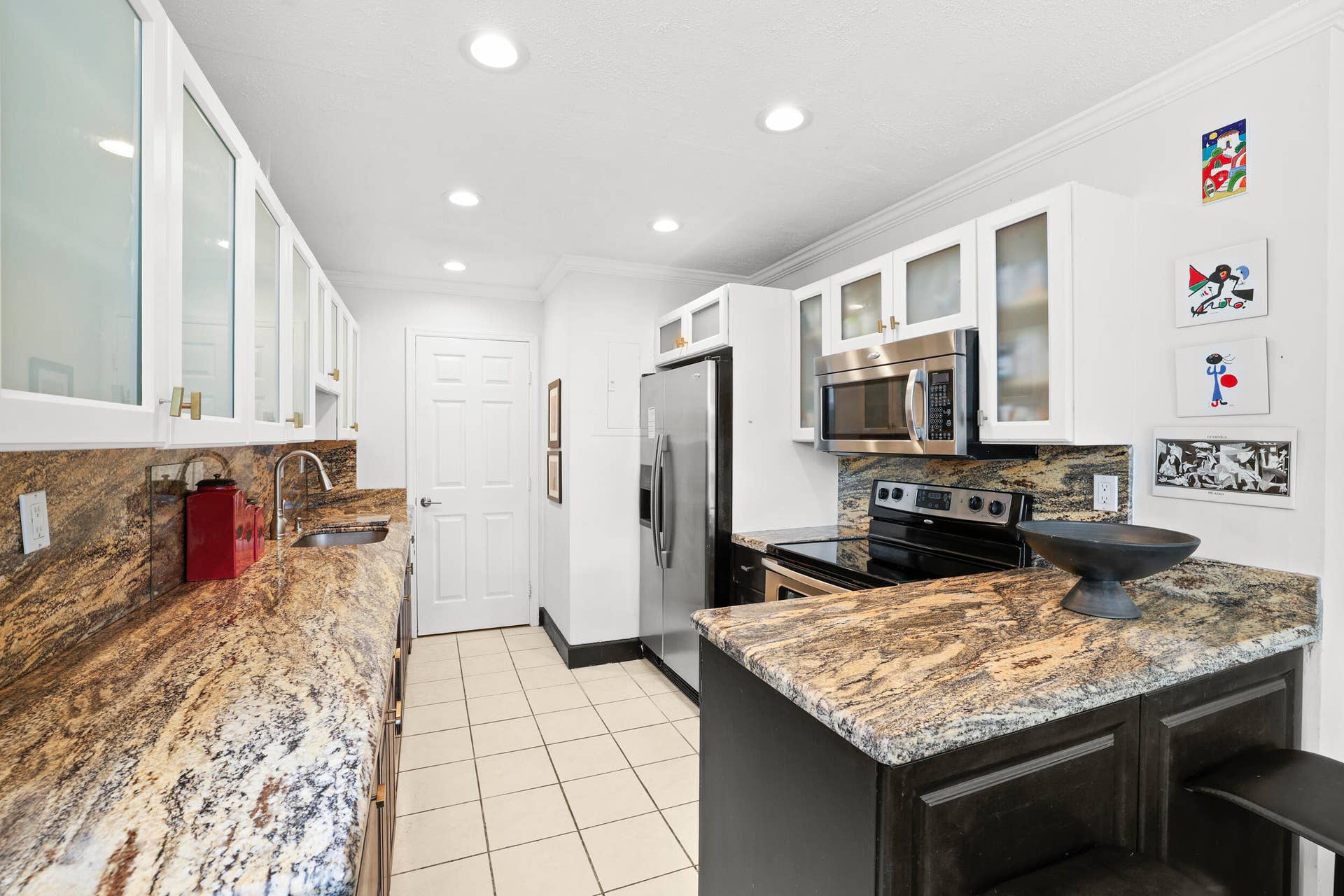 7 Middlesex Drive, Wilton Manors, FL 33305 Galley kitchen featuring granite countertops, stainless steel appliances, white cabinetry with glass-front upper cabinets, recessed lighting, and a center island with additional workspace and storage