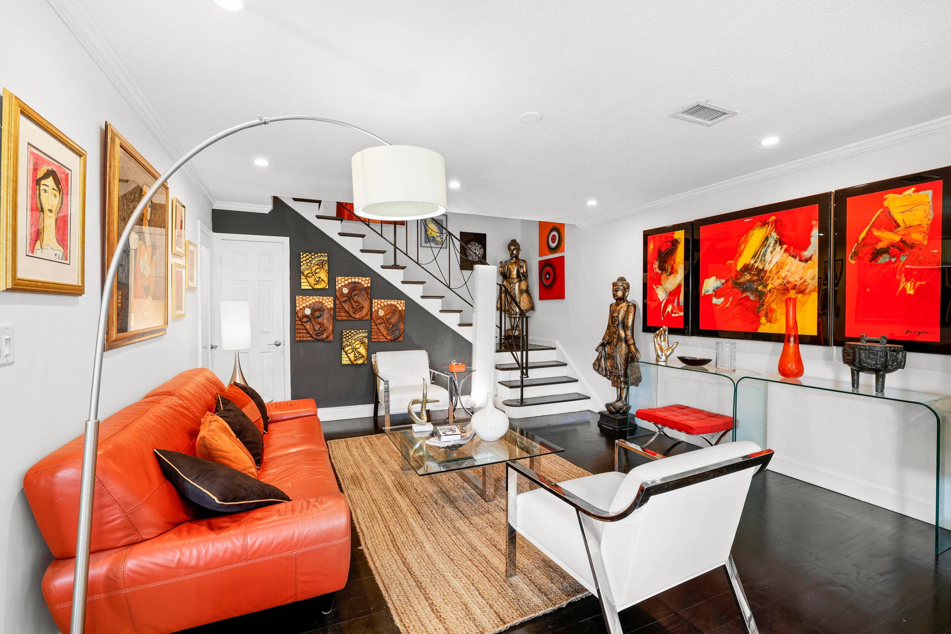 7 Middlesex Drive, Wilton Manors, FL 33305 Contemporary living space featuring a striking red leather sectional, polished wood-finish flooring, and a dramatic arc floor lamp