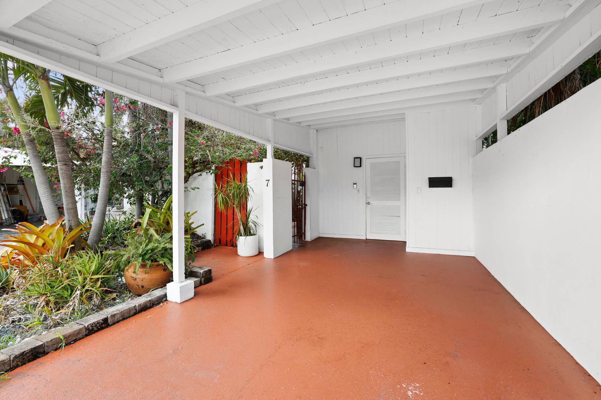 7 Middlesex Drive, Wilton Manors, FL 33305 Covered carport featuring a white exposed beam ceiling and terracotta-hued flooring