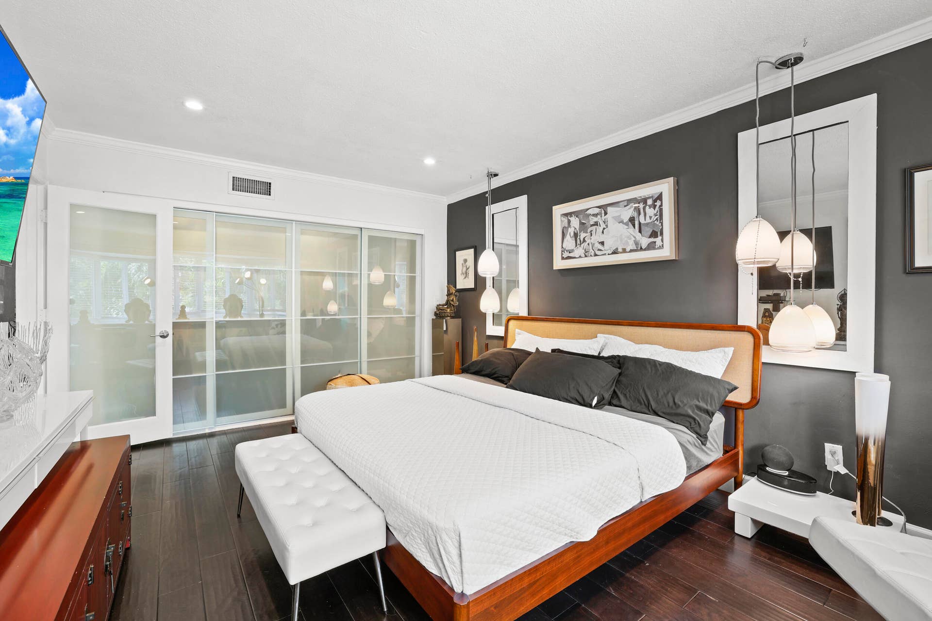 7 Middlesex Drive, Wilton Manors, FL 33305 Sophisticated primary bedroom showcasing a warm wood-finish platform bed frame, crisp white bedding, and dual upholstered benches