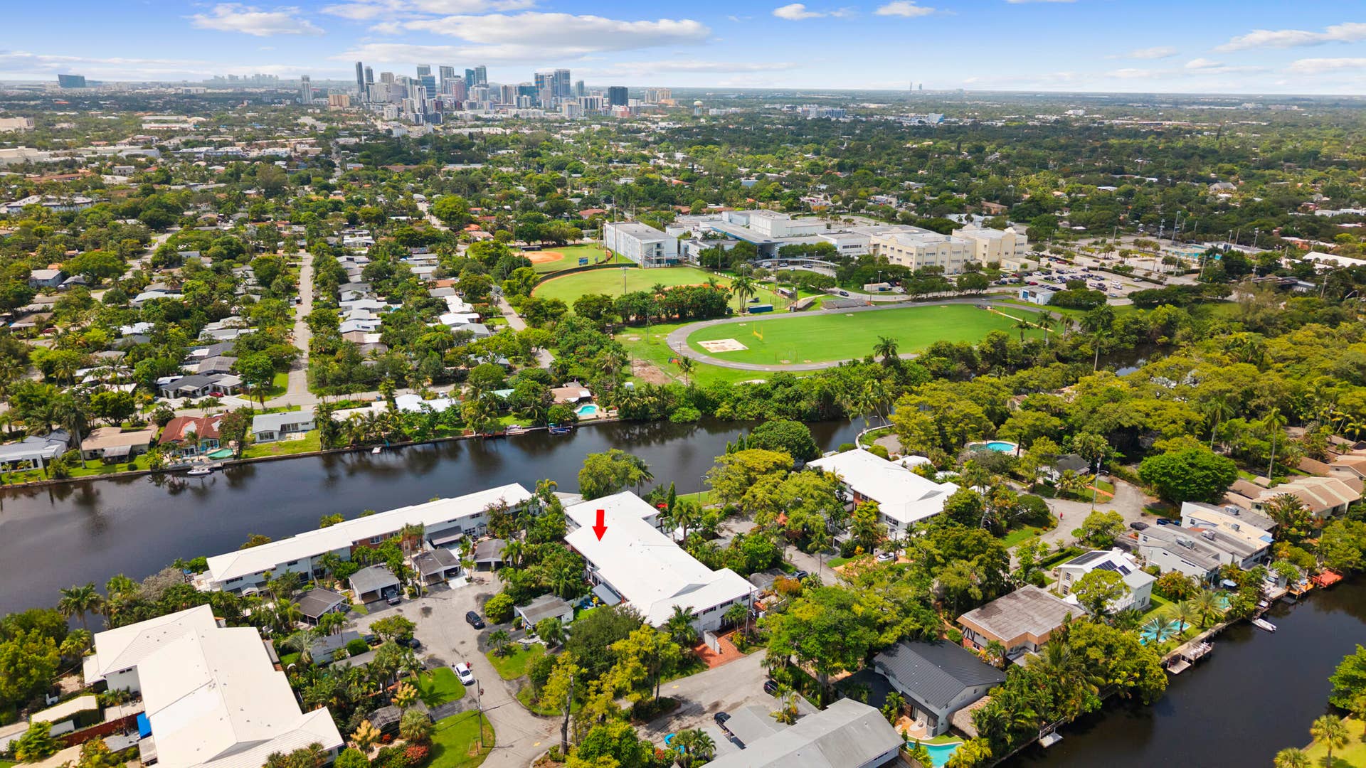 7 Middlesex Drive, Wilton Manors, FL 33305 Aerial perspective showcasing this waterfront property's expansive grounds featuring manicured lawn, mature tree canopy, and direct water access