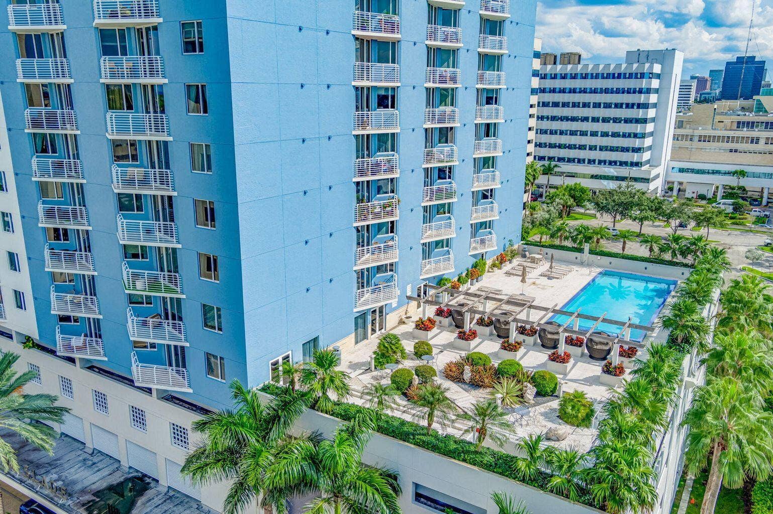 Rooftop amenity deck featuring a swimming pool, lounge areas with pergolas, and structured landscaping with palm trees