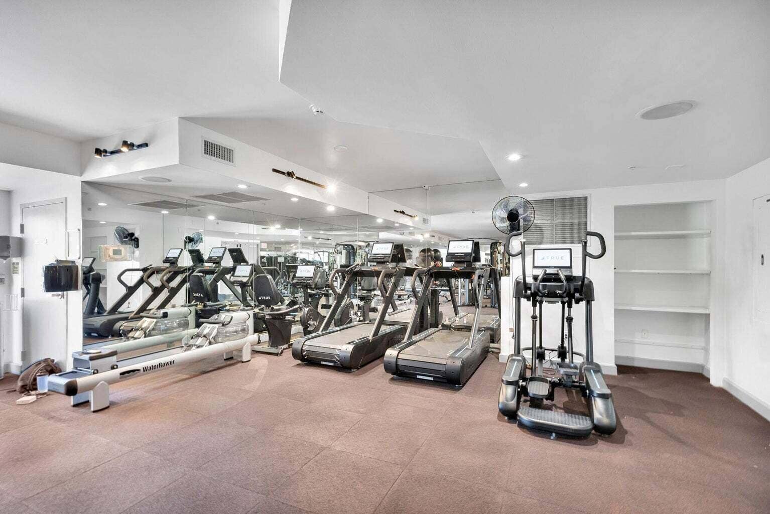 Fitness center featuring mirrored walls, recessed lighting, and built-in shelving