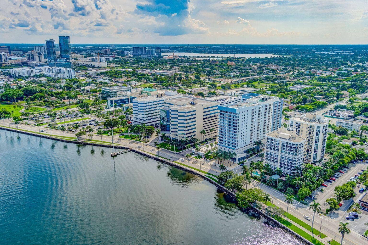 Waterfront property featuring multiple high-rise buildings, a marina with boat slips, and a tree-lined promenade
