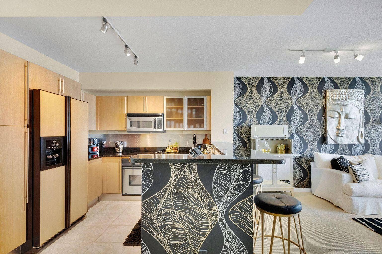Open-concept living space with a kitchen featuring light wood-finish cabinetry and stainless steel appliances